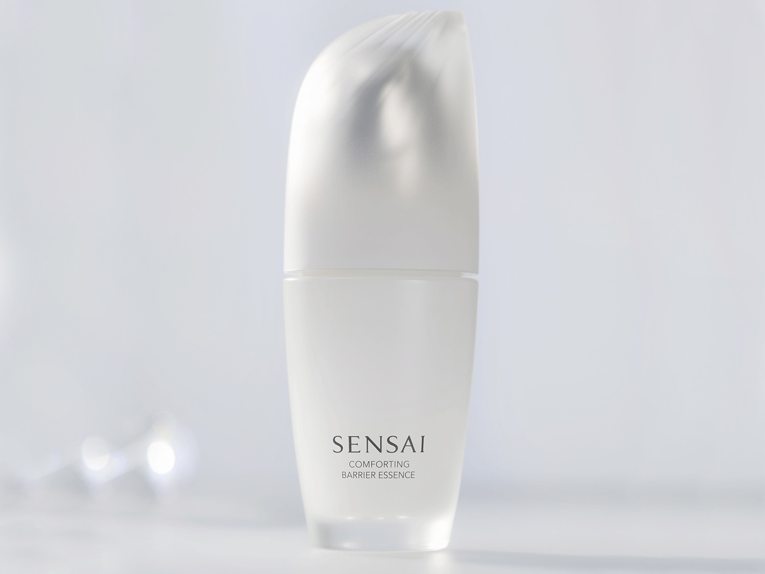 SENSAI Comforting Barrier Essence v bílé skleněné lahvičce s matným povrchem, která slibuje zklidnění a posílení kožní bariéry.