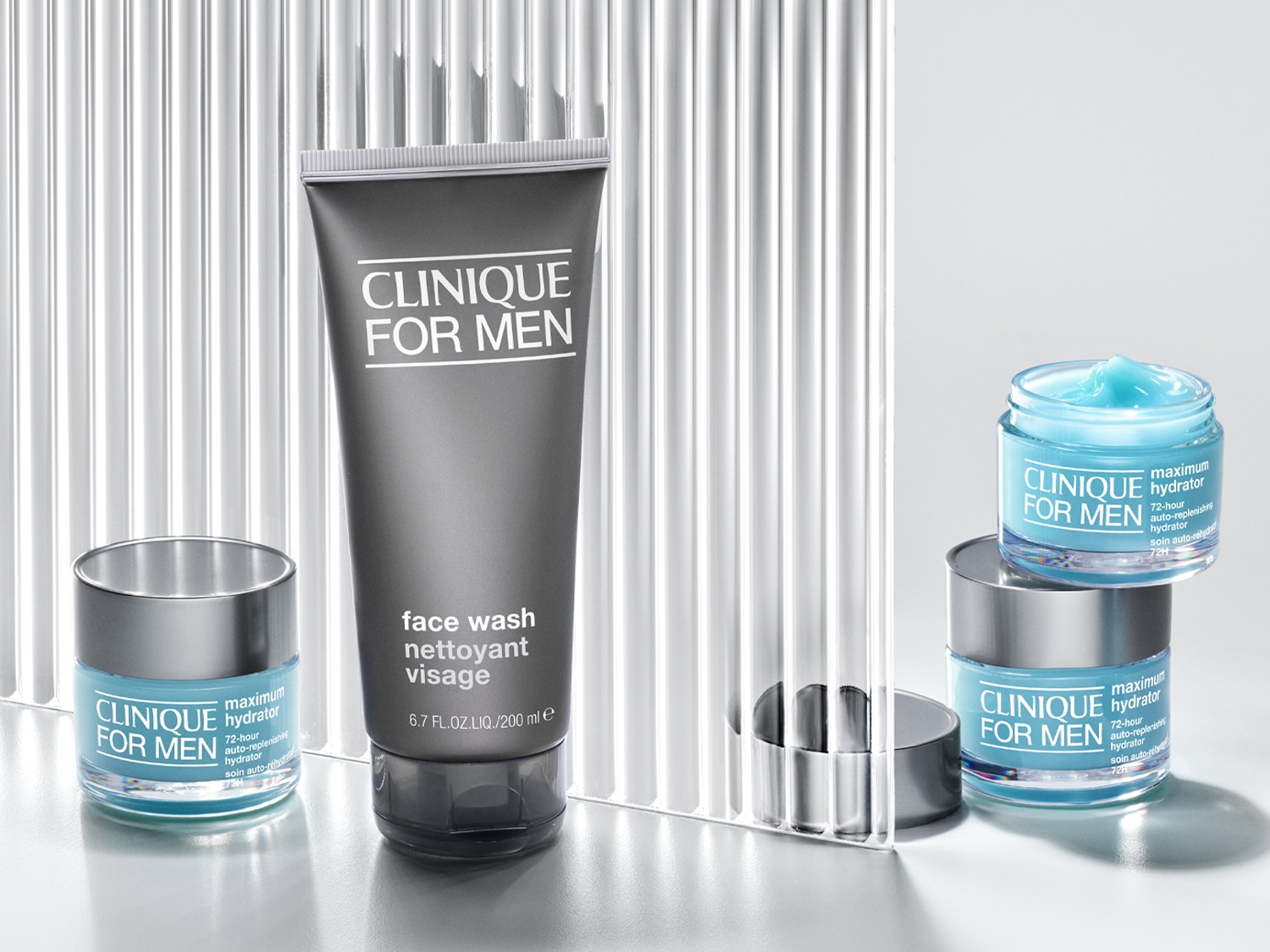 A Clinique For Men termékcsalád látható, beleértve egy szürke arctisztító tubust és két hidratáló tégelyt, amelyek frissítő, kék színűek.