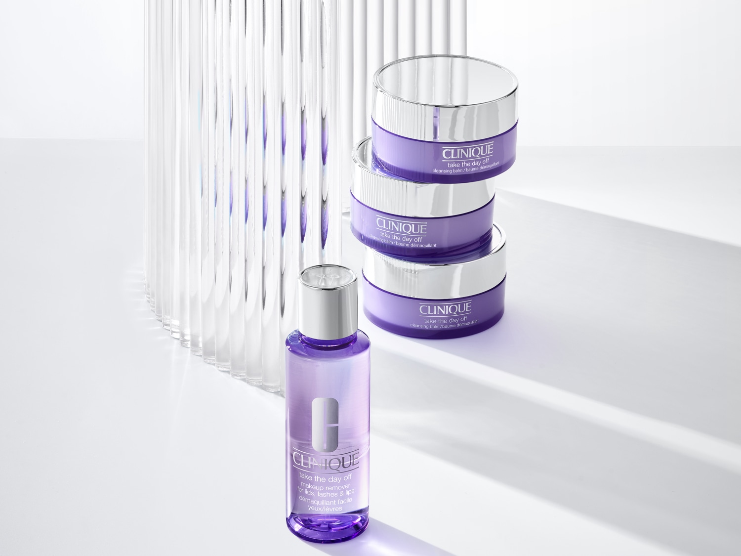 A Clinique Take the Day Off termékei láthatók: sminklemosó lila üvegben és tisztító balzsam lila tégelyben, ezüst fedéllel.