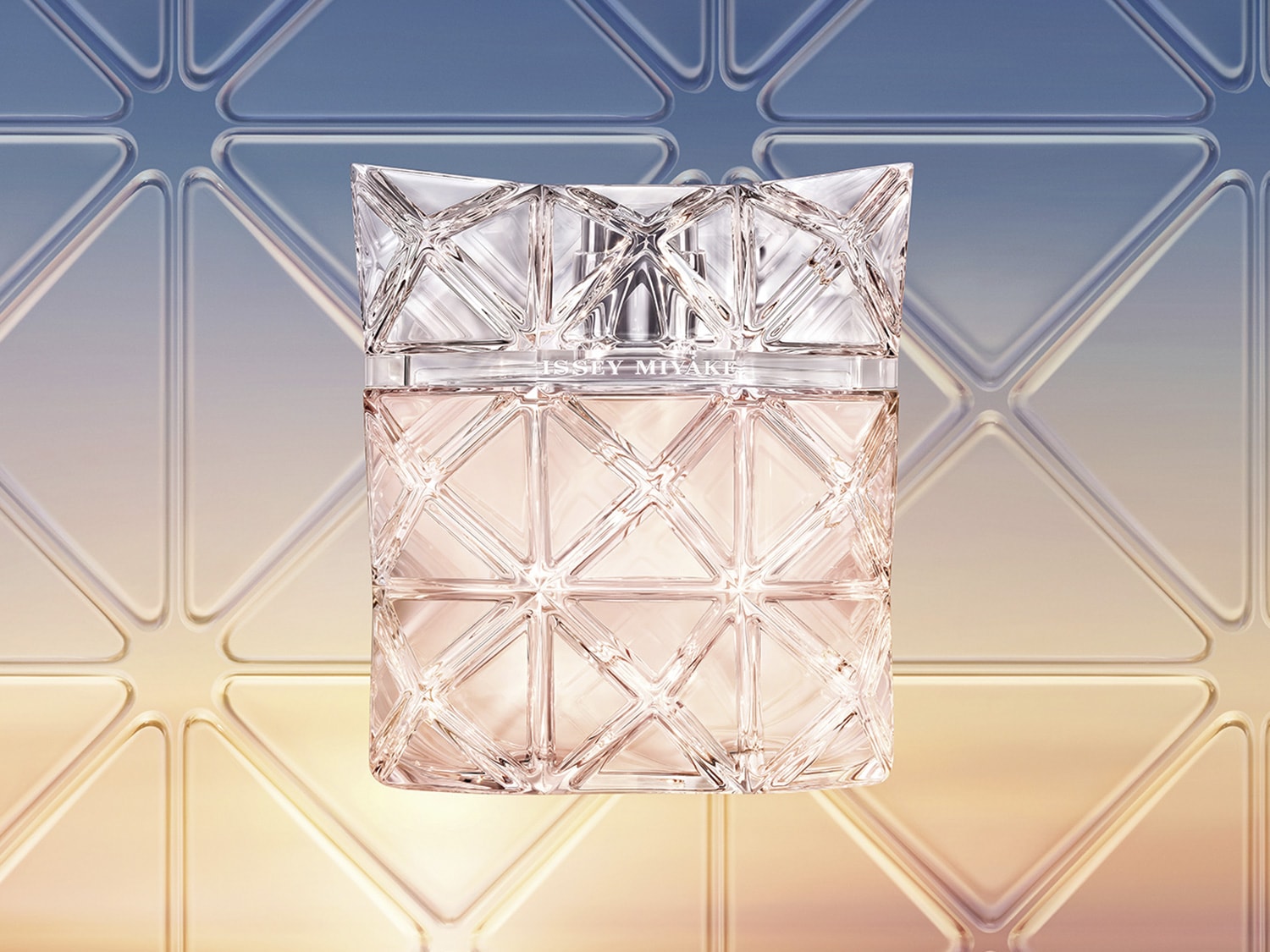 El frasco de perfume Issey Miyake presenta un diseño geométrico transparente que revela un líquido de color rosa pálido en su interior.