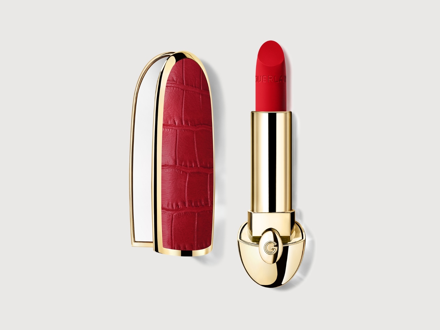 Aquí tienes un labial rojo de Guerlain con un estuche dorado y una funda roja con textura de cocodrilo, ideal para un look sofisticado.