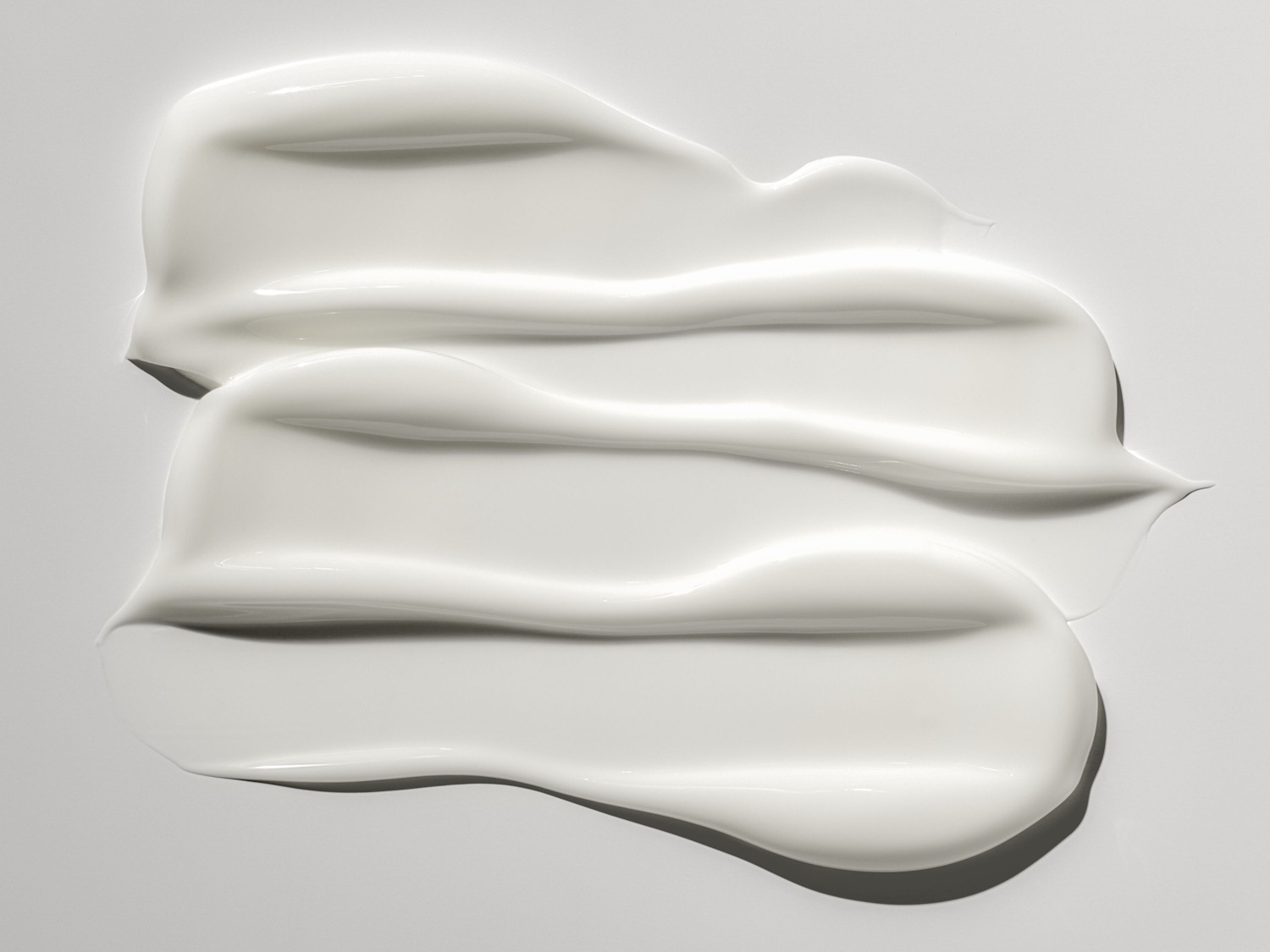 Nahaufnahme von drei glänzenden, weißen Creme Klecksen, die eine reichhaltige Textur und Feuchtigkeitspflege suggerieren.