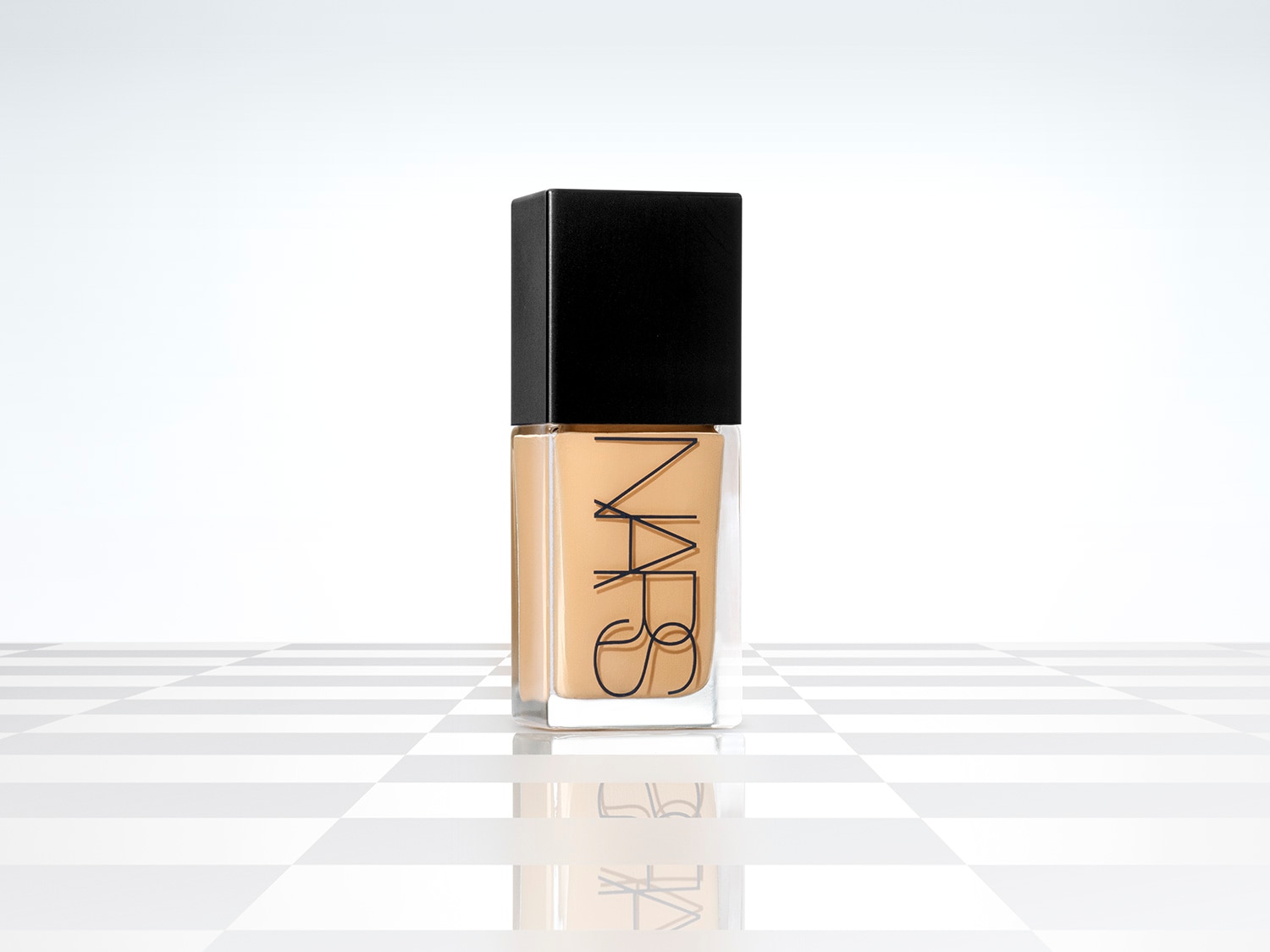 Base de maquillaje NARS en frasco de vidrio transparente con tapa negra, mostrando un tono beige claro, ideal para un cutis impecable.