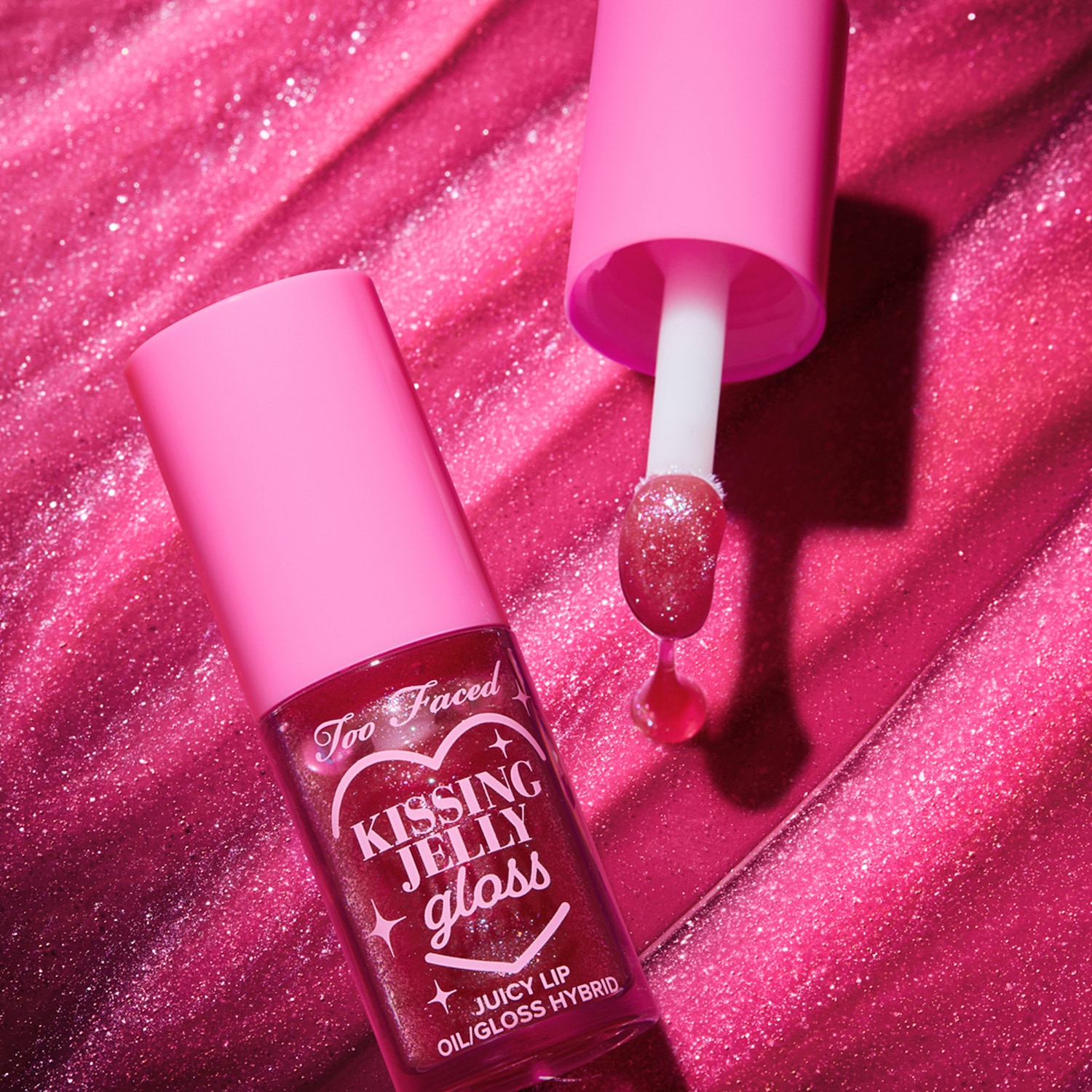 Découvrez le brillant à lèvres Kissing Jelly de Too Faced, un hybride huile/gloss juteux dans un emballage rose éclatant, parfait pour des lèvres irrésistibles.
