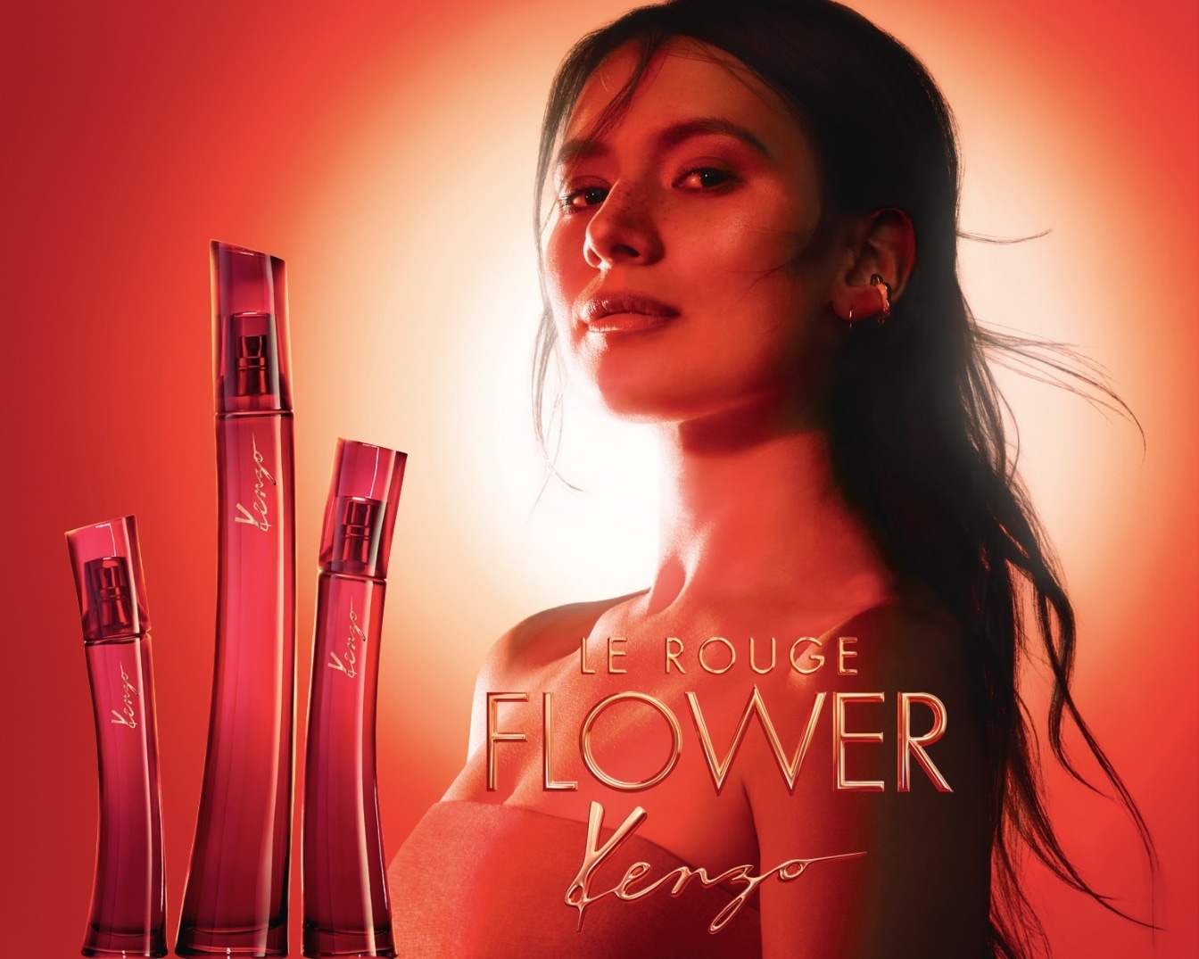 Rote Kenzo-Parfümflaschen stehen neben einer Frau mit dunklen Haaren vor einem roten Hintergrund, der Duft heißt Le Rouge Flower.