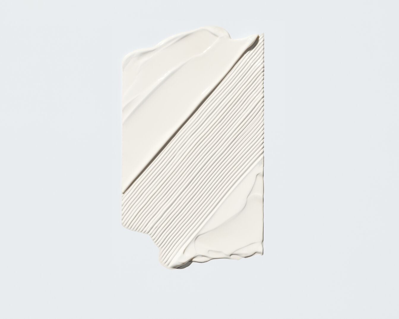 Nahaufnahme eines weißen Cremeprodukts, das in dicken, glatten Streifen aufgetragen wurde und eine reichhaltige, feuchtigkeitsspendende Textur zeigt.