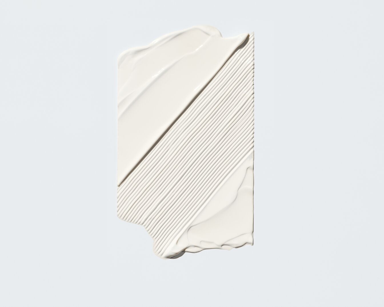 Nahaufnahme eines weißen Cremeprodukts, das in dicken, glatten Streifen aufgetragen wurde und eine reichhaltige, feuchtigkeitsspendende Textur zeigt.