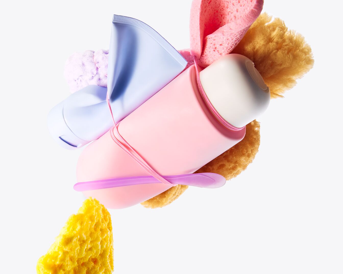 Roze en blauwe huidverzorgingsproducten, waaronder een tube en een pot, zijn gerangschikt met sponzen in verschillende kleuren.