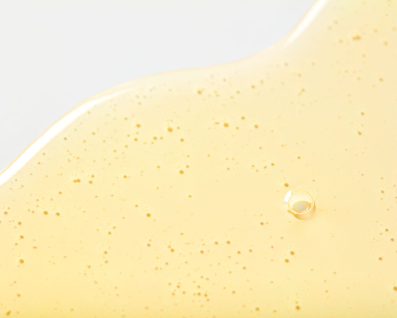 Gouden serum textuur met kleine luchtbelletjes, glanzend en glad.