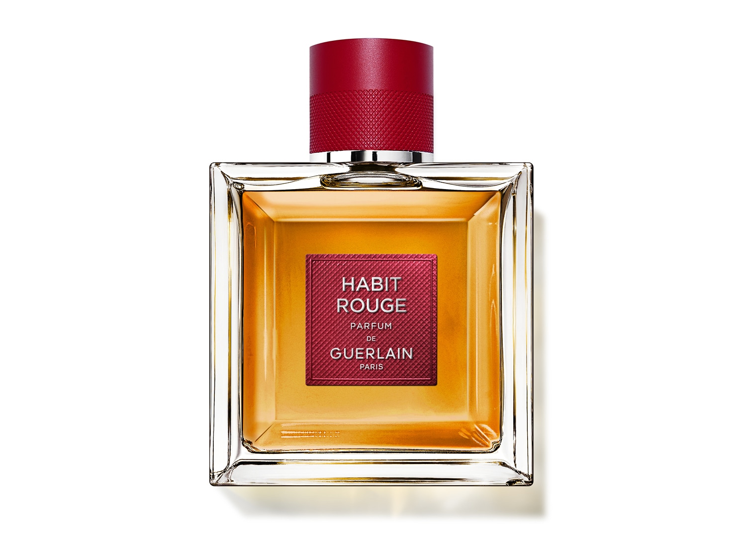 Kwadratowa butelka perfum Habit Rouge marki Guerlain z czerwoną etykietą i korkiem, wypełniona bursztynowym płynem.