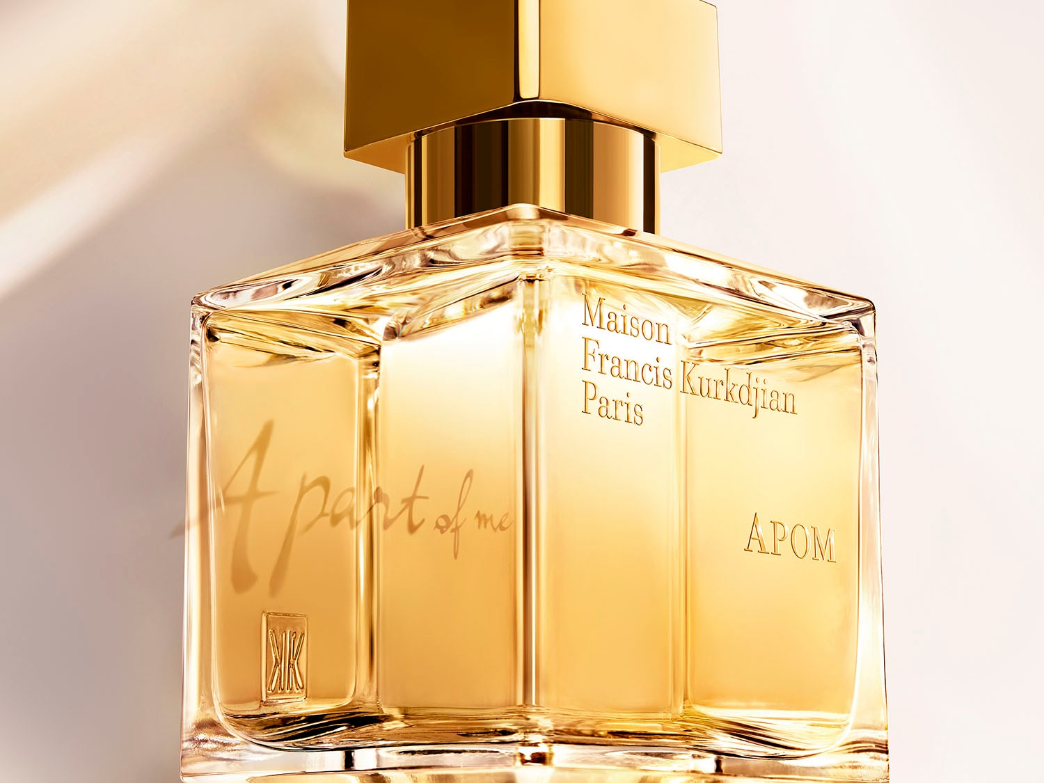 Nahaufnahme des Maison Francis Kurkdjian Paris APOM Parfüms, dessen goldener Farbton und klare Flasche Eleganz versprechen.