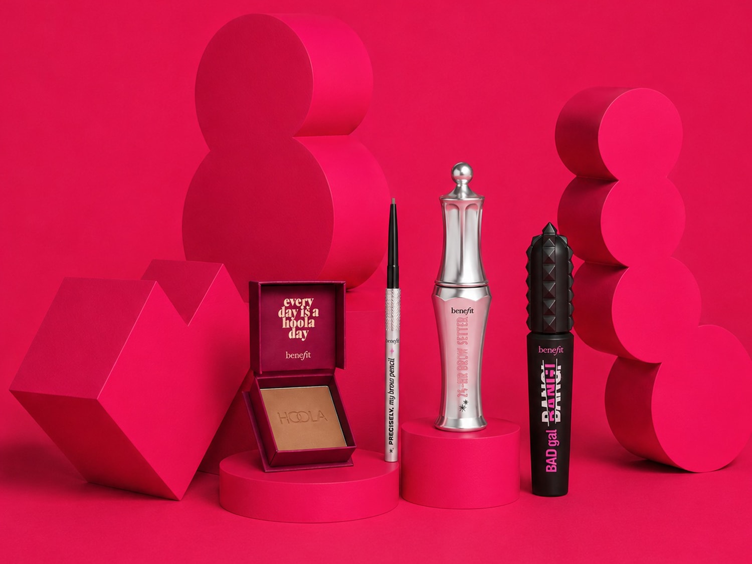 Een Benefit Cosmetics make-up set met Hoola bronzer, Precisely My Brow Pencil, 24-HR Brow Setter en Bad Gal Bang mascara, gepresenteerd op roze geometrische vormen.