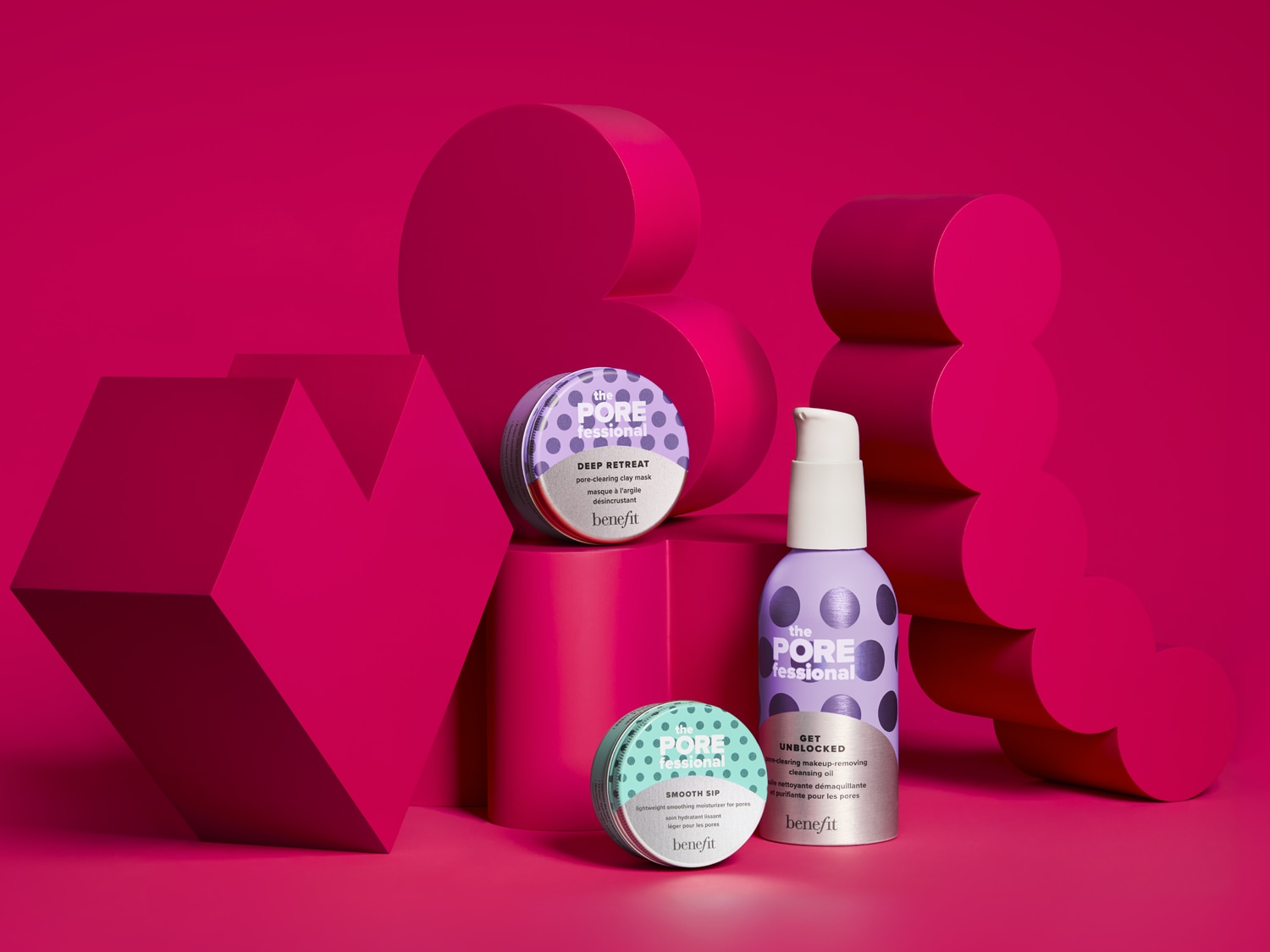 Drie Benefit The POREfessional producten, waaronder een paars potje "Deep Retreat" kleimasker, een lichtpaarse fles "Get Unblocked" reinigingsolie en een mintgroen potje "Smooth Sip" moisturizer, staan op roze geometrische blokken tegen een felroze achtergrond.