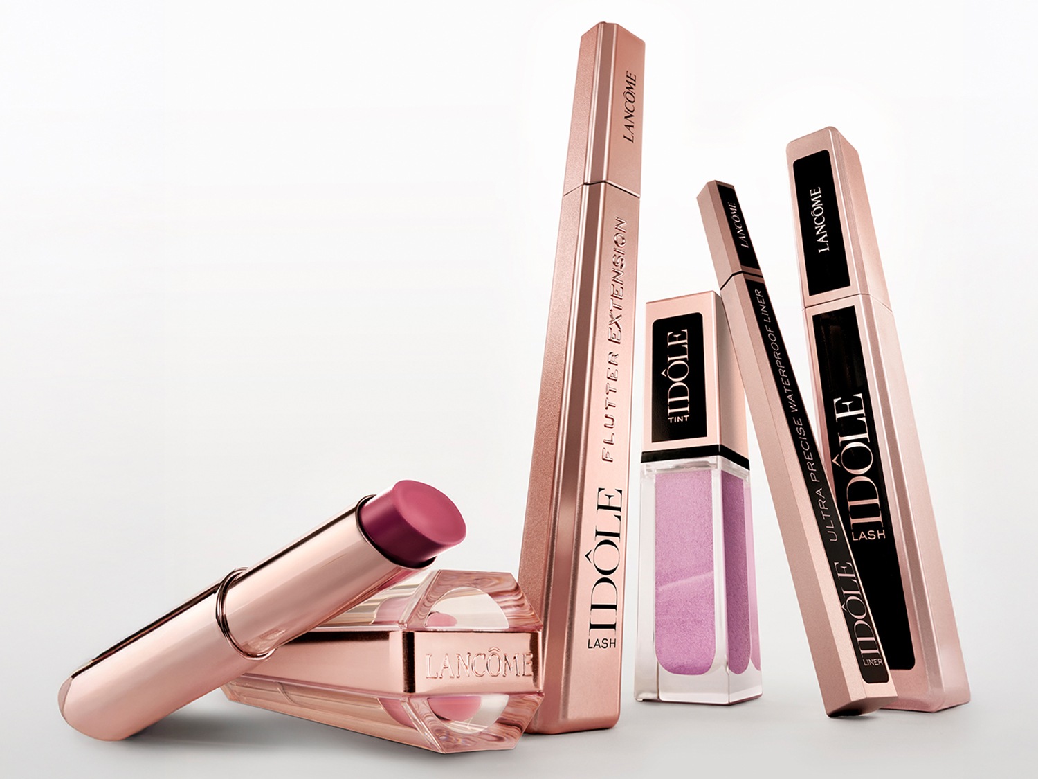 Découvrez un assortiment de produits de beauté Lancôme, comprenant des mascaras Idôle Lash et Flutter Extension dans des emballages élégants rose doré, un eye-liner de précision et un rouge à lèvres rose.