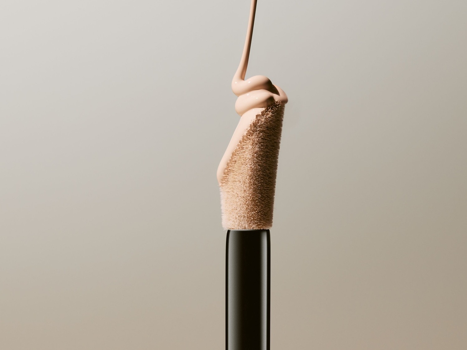 Nahaufnahme eines Concealer-Applikators mit beiger Flüssigkeit, die heruntertropft, ideal zum Abdecken von Hautunreinheiten.