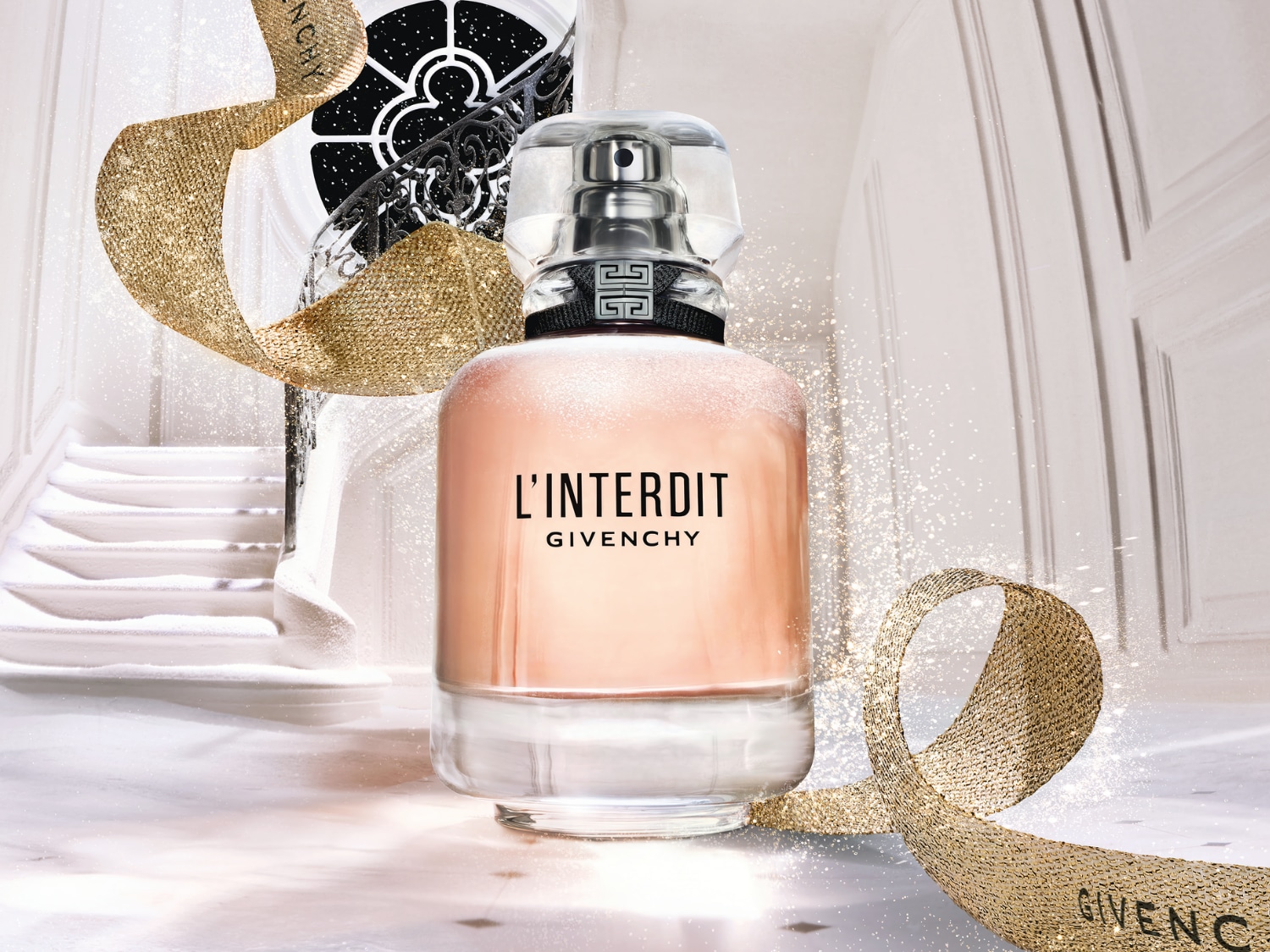 Ein Flakon L'Interdit Givenchy Eau de Parfum steht vor einer weißen Treppe, umgeben von goldenem Glitzerband, das Eleganz und festlichen Glanz versprüht.