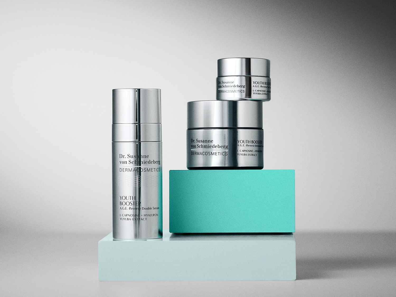 Découvrez le sérum et la crème Youth Booster de Dr. Susanne von Schmiedeberg, présentés dans des emballages argentés élégants, promettant une peau rajeunie avec L-Carnosine et extrait de Yuyuba.