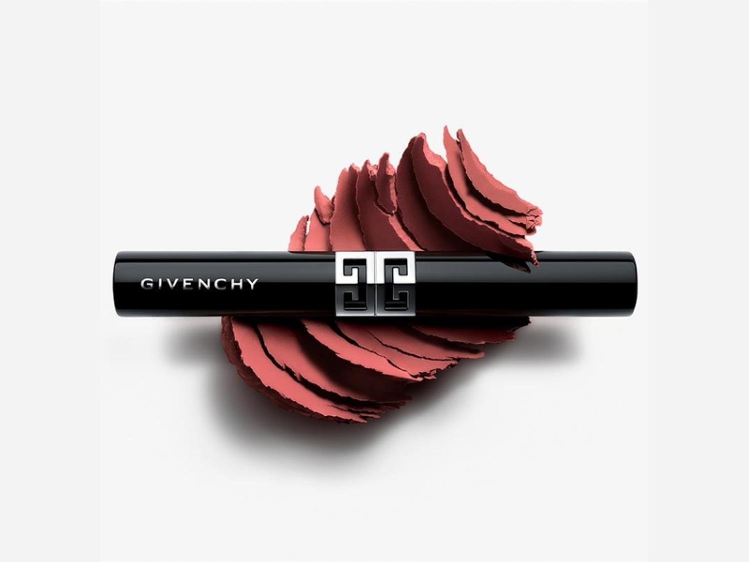 Découvrez le rouge à lèvres Givenchy dans son élégant tube noir, orné du logo emblématique, présenté sur un éventail de poudre rose corail.