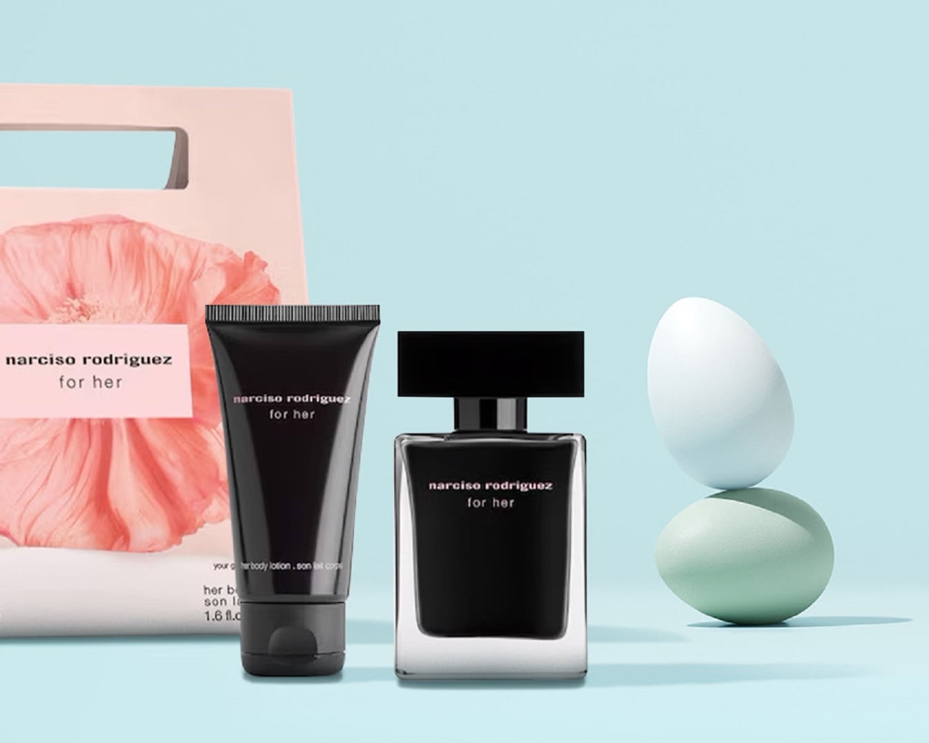 Das Narciso Rodriguez for Her Set mit einem eleganten, schwarzen Parfümflakon, einer Bodylotion in einer schwarzen Tube und einer zartrosa Geschenkverpackung mit Blumenmuster.