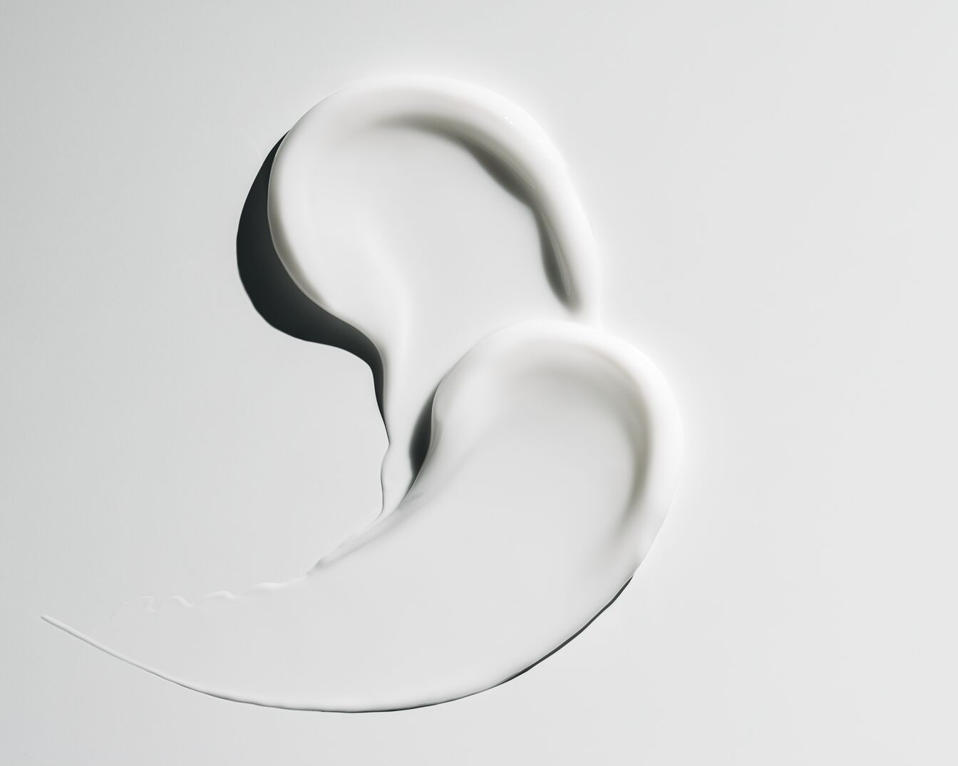 Kremowa, biała maź o gładkiej teksturze na jasnym tle, idealna do pielęgnacji skóry.