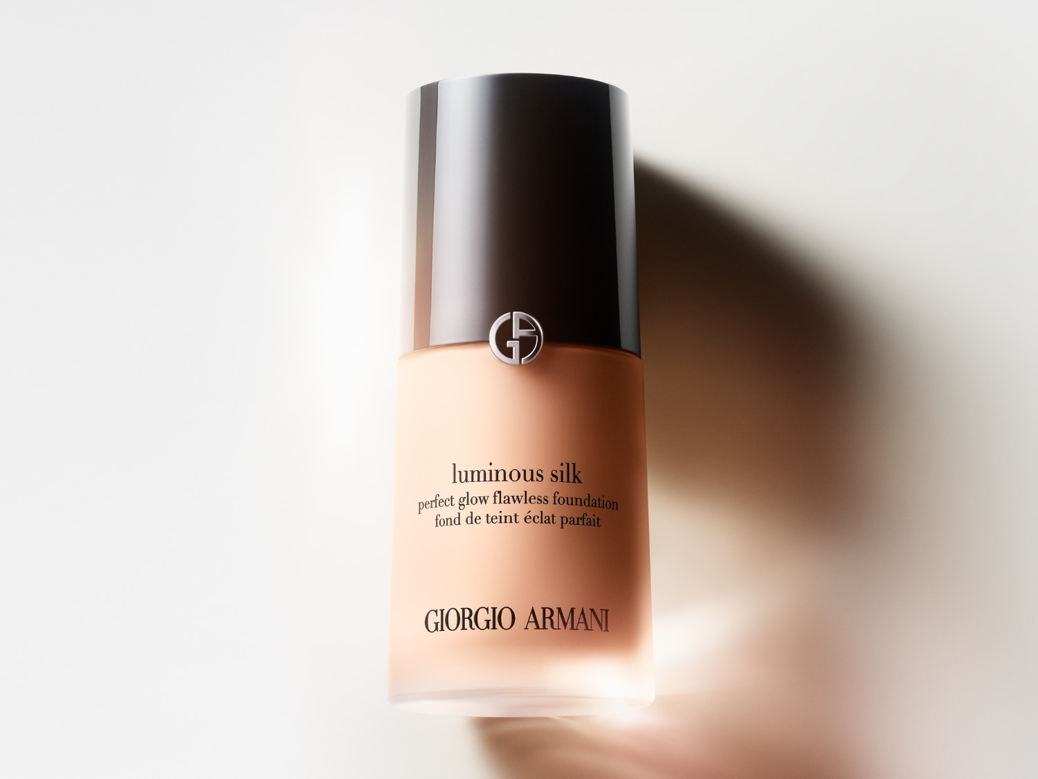 Lahvička make-upu Giorgio Armani Luminous Silk s černým víčkem a béžovým obsahem slibuje dokonalý a zářivý vzhled pleti.