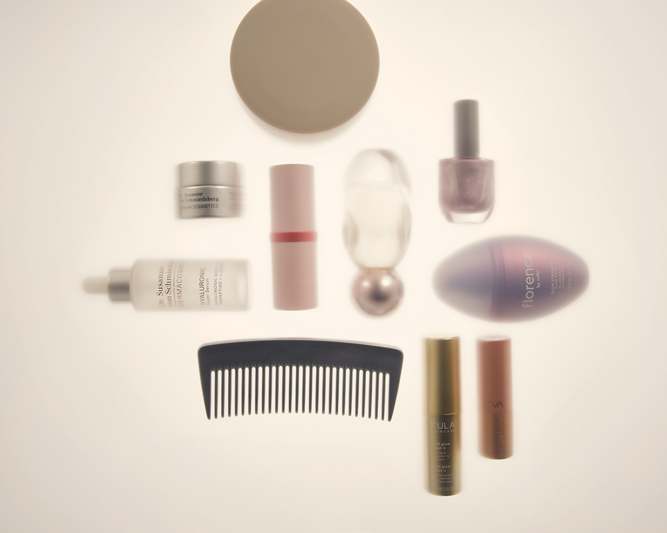 Een verzameling schoonheidsproducten, waaronder crèmes, lippenstiften, nagellak en een kam, gerangschikt op een witte achtergrond.