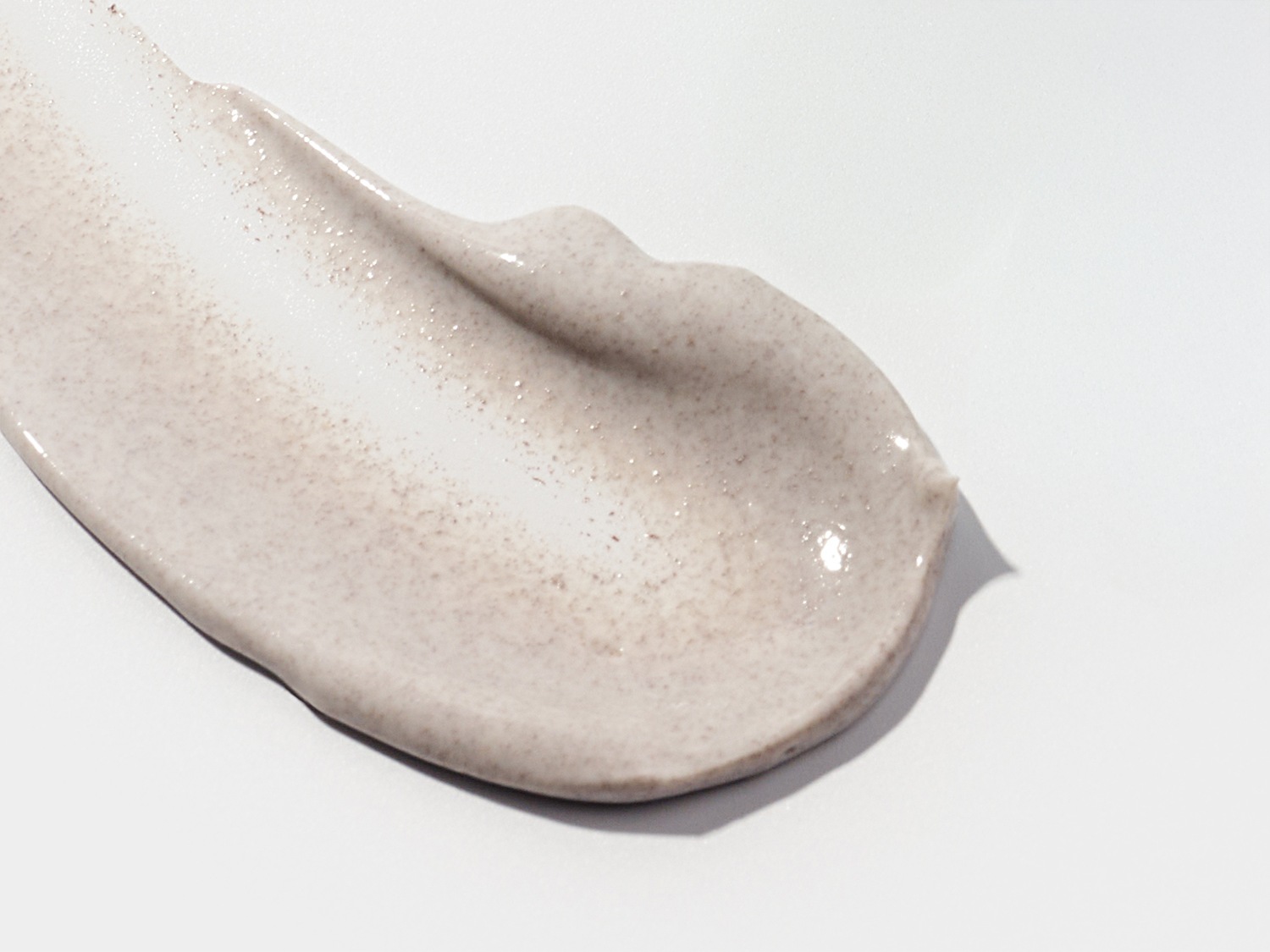 Voici une noisette de crème exfoliante beige clair, parsemée de fines particules, offrant une texture lisse et brillante.