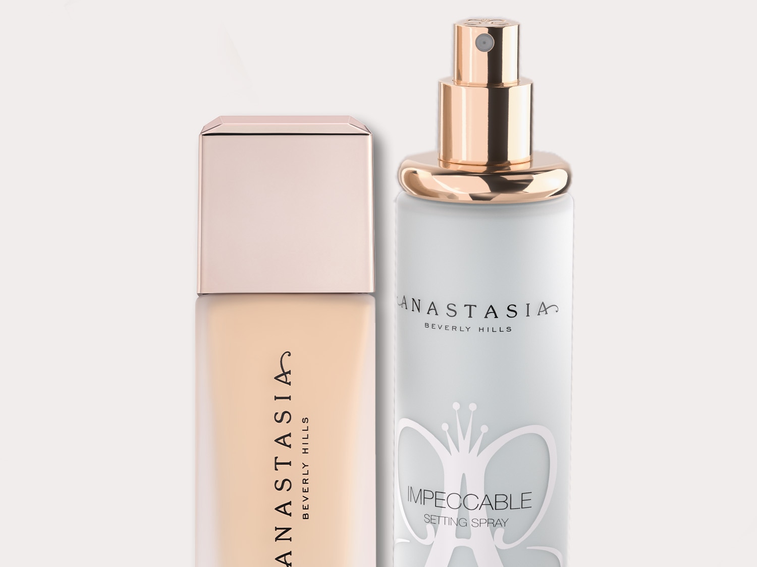 Dwa produkty do makijażu marki Anastasia Beverly Hills: podkład w beżowym opakowaniu z kwadratową nakrętką i biały spray utrwalający z elementami w kolorze złotym.