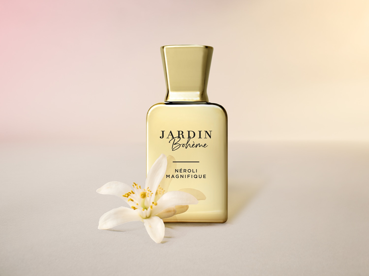 Gouden flacon Jardin Bohème Néroli Magnifique parfum, met een witte bloem op de voorgrond, straalt luxe en verfijning uit.