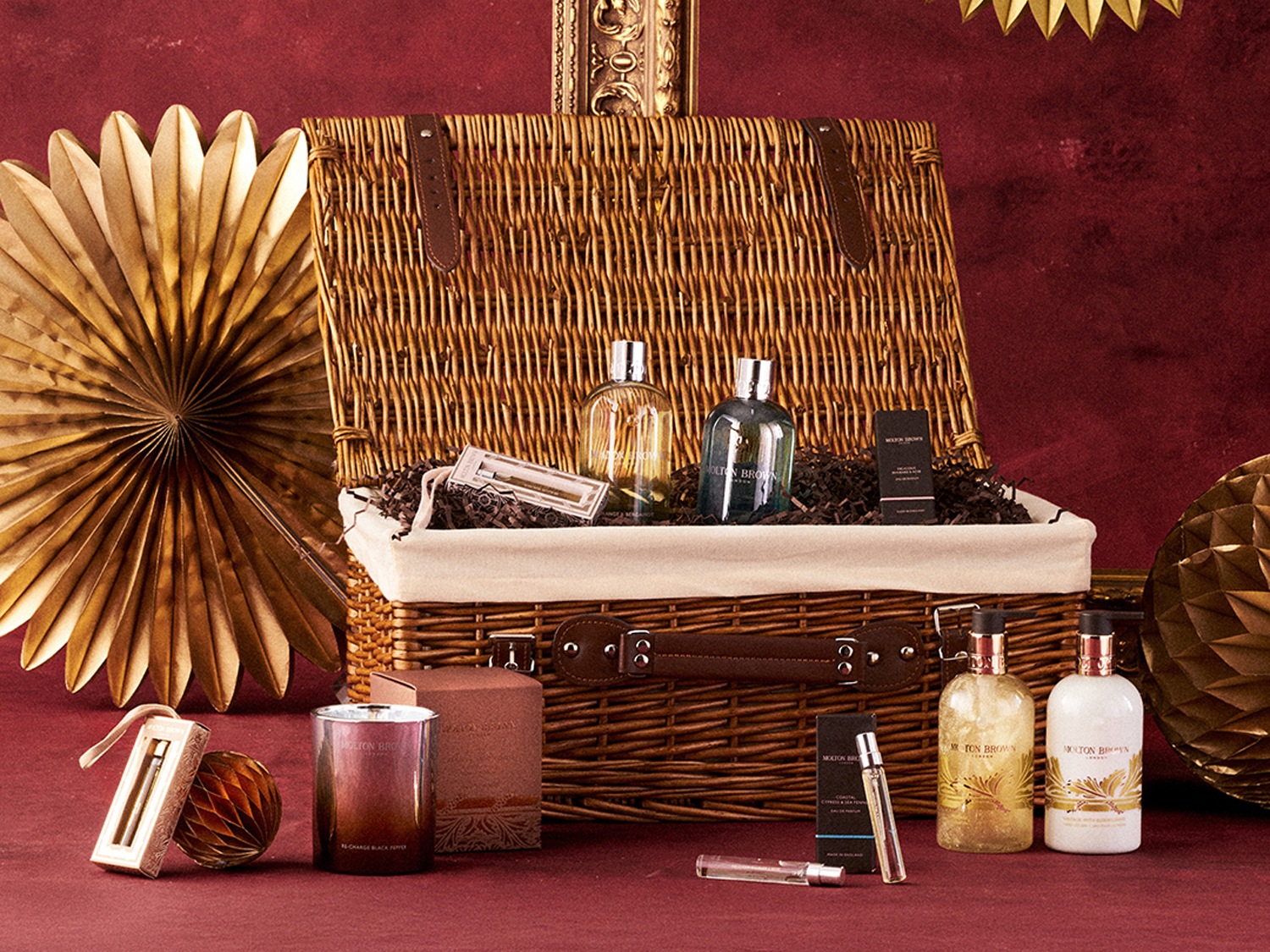 Darčekový kôš Molton Brown s parfumami, sviečkami a telovou kozmetikou v zlatom a hnedom balení, ideálny ako luxusný darček.