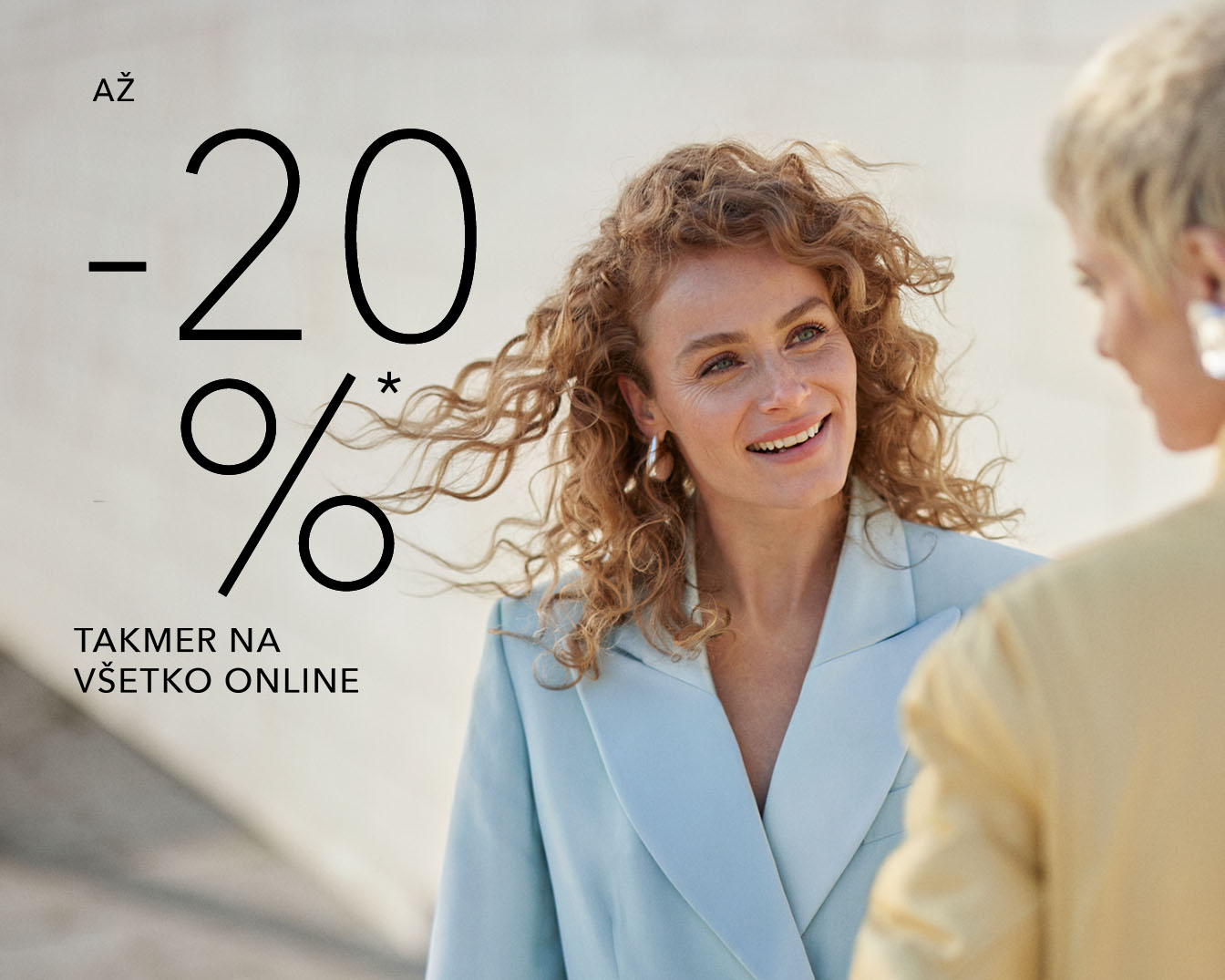 Až -20 % takmer na všetko online, usmievavá žena s kučeravými vlasmi v modrom saku.