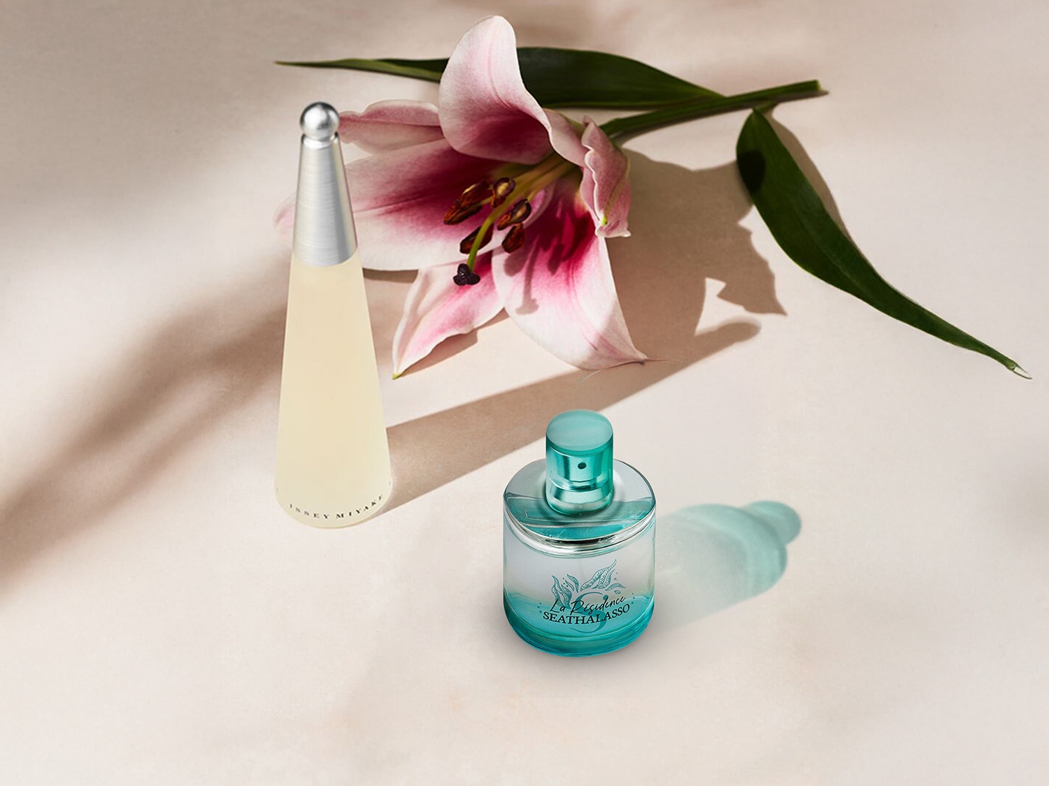 Twee parfumflessen, een kegelvormige Issey Miyake en een ronde La Rive Seathalasso, staan naast een roze lelie op een zachte achtergrond.
