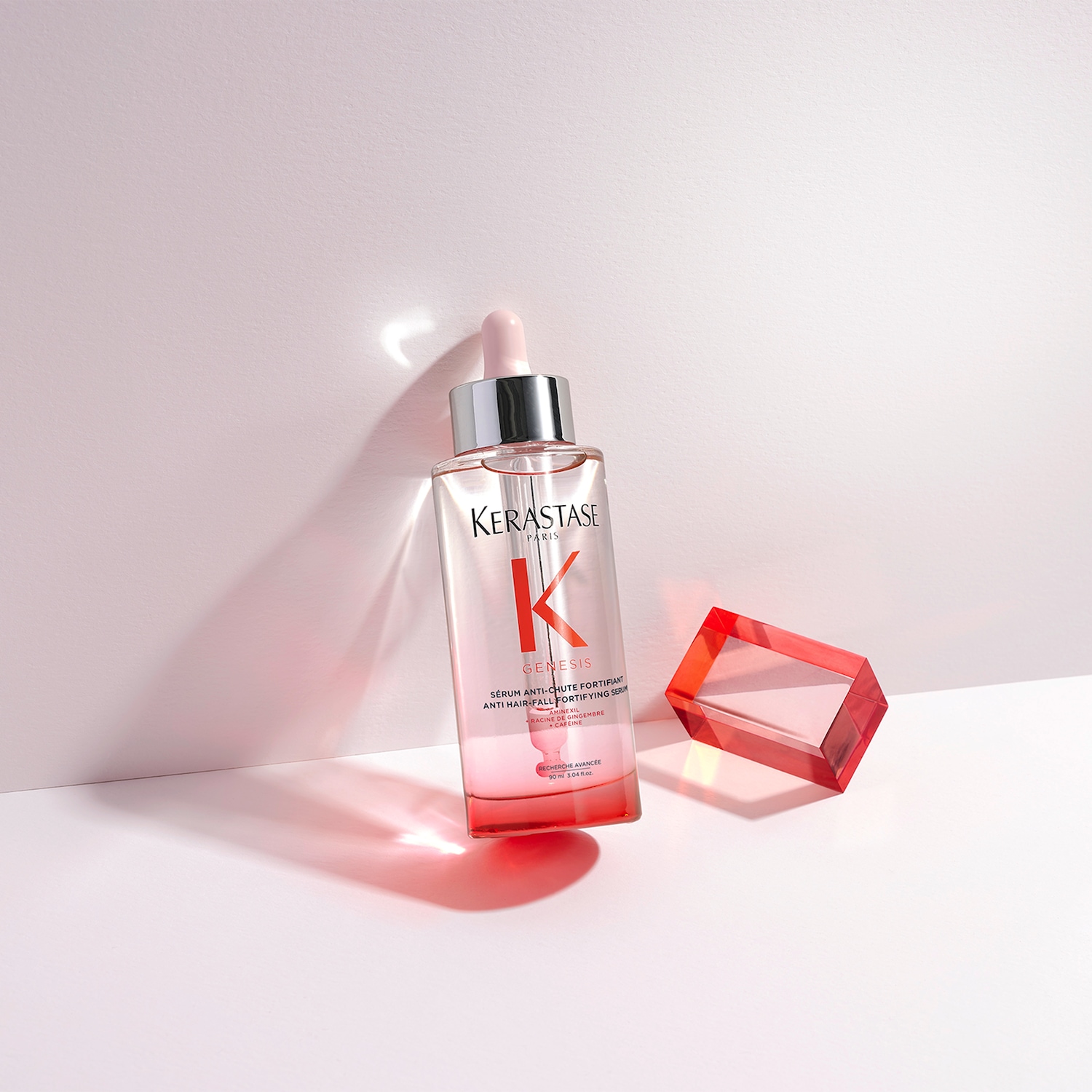 Das Kerastase Genesis Serum in einer durchsichtigen Flasche mit silbernem Verschluss und einem rosa Farbverlauf stärkt das Haar und reduziert Haarausfall.