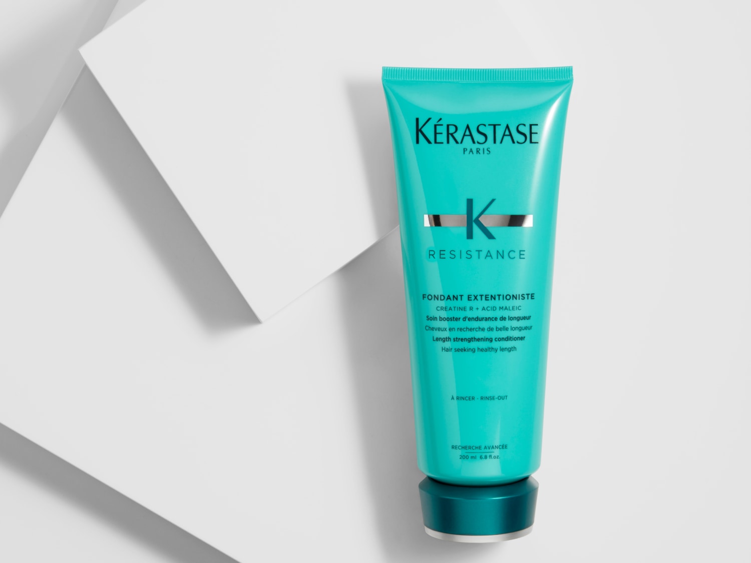 Die türkisfarbene Tube Kérastase Resistance Fondant Extentioniste Spülung stärkt das Haar und fördert gesundes, langes Haar.