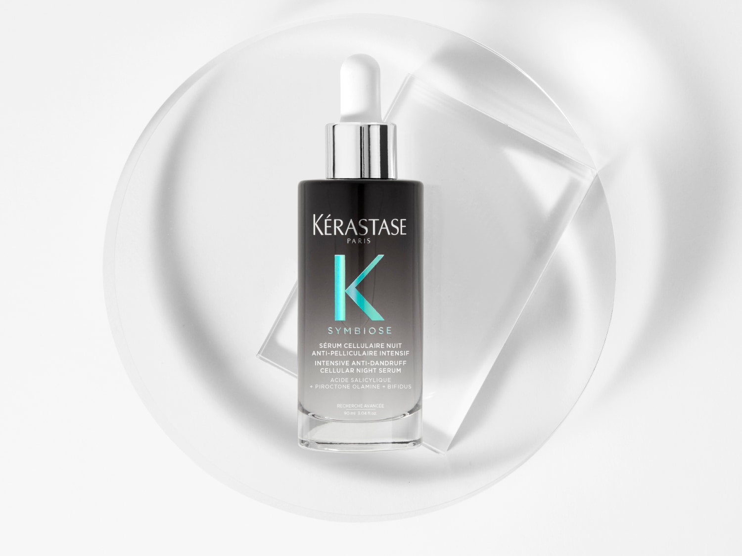 Das Kérastase Symbiose Serum Cellulaire Nuit Anti-Pelliculaire Intensif in einer schwarz-silbernen Flasche mit Pipette, das für eine intensive Anti-Schuppen-Behandlung über Nacht sorgt.