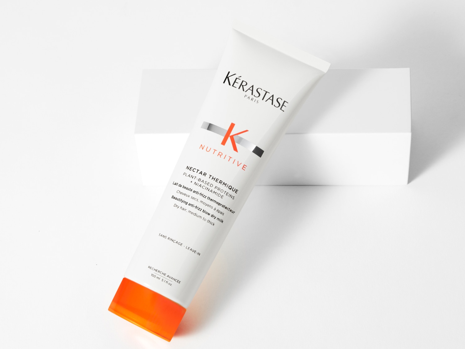 Die weiße Tube Kérastase Nectar Thermique Hitzeschutz-Milch mit orangefarbenen Akzenten verspricht Anti-Frizz für trockenes, mitteldickes bis dickes Haar.