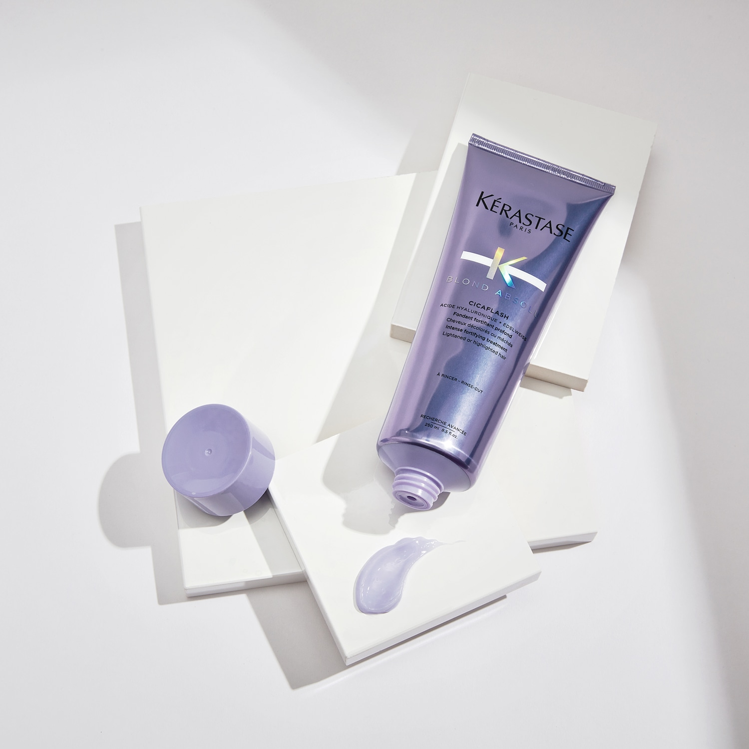 Kérastase Paris Blond Absolu Cicaflash: Eine intensiv stärkende Behandlung mit Hyaluronsäure und Edelweiss für aufgehelltes oder gesträhntes Haar in einer lila Tube.