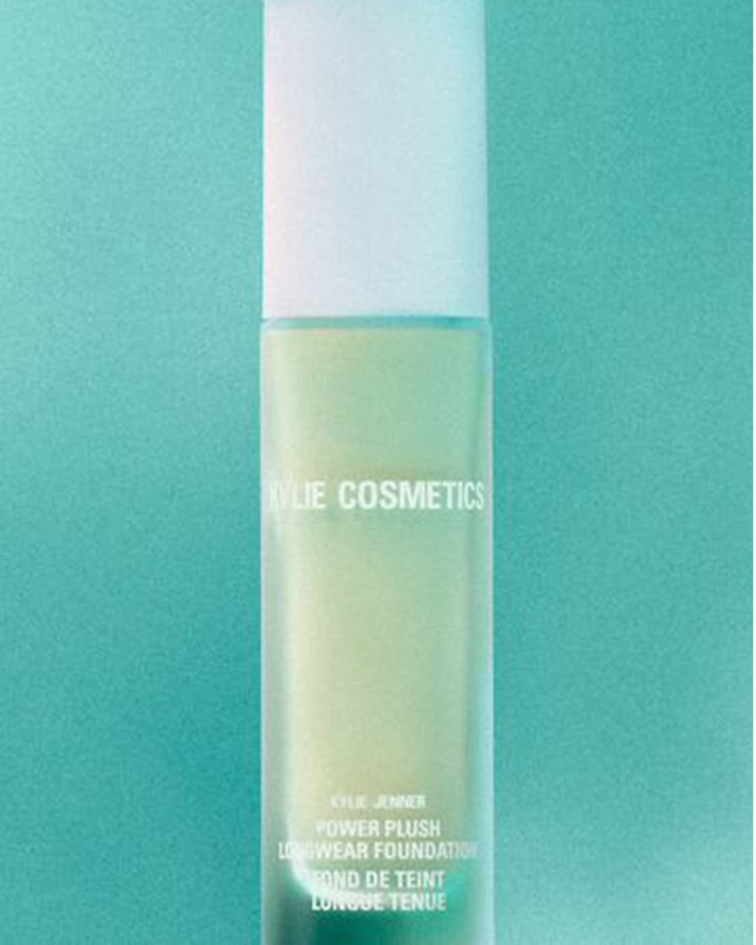 Kylie Cosmetics Power Plush Longwear Foundation buteliukas su baltu dangteliu ir šviesiai žalios spalvos pagrindu, skirtas ilgalaikiam makiažui.