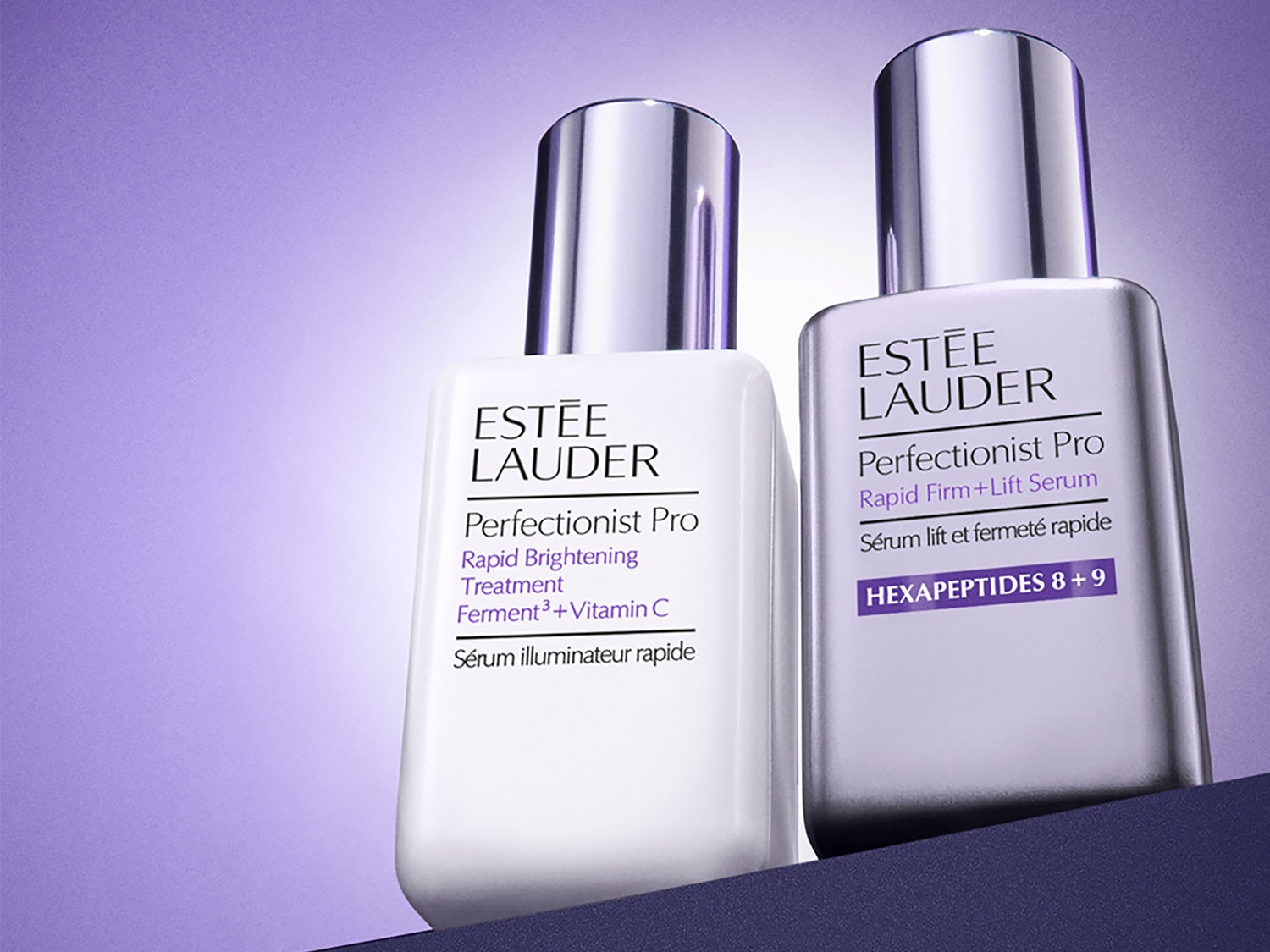 Zwei Flaschen Estée Lauder Perfectionist Pro Serum, eine für schnelle Aufhellung mit Ferment³ + Vitamin C in weißer Verpackung, die andere für schnelle Straffung und Lifting mit Hexapeptiden 8 + 9 in silberner Verpackung.