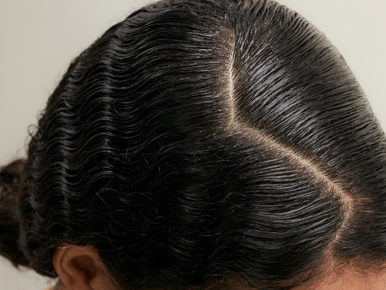 Nahaufnahme von glänzendem, gewelltem, dunklem Haar, das sauber gescheitelt ist und einen gepflegten Look zeigt.