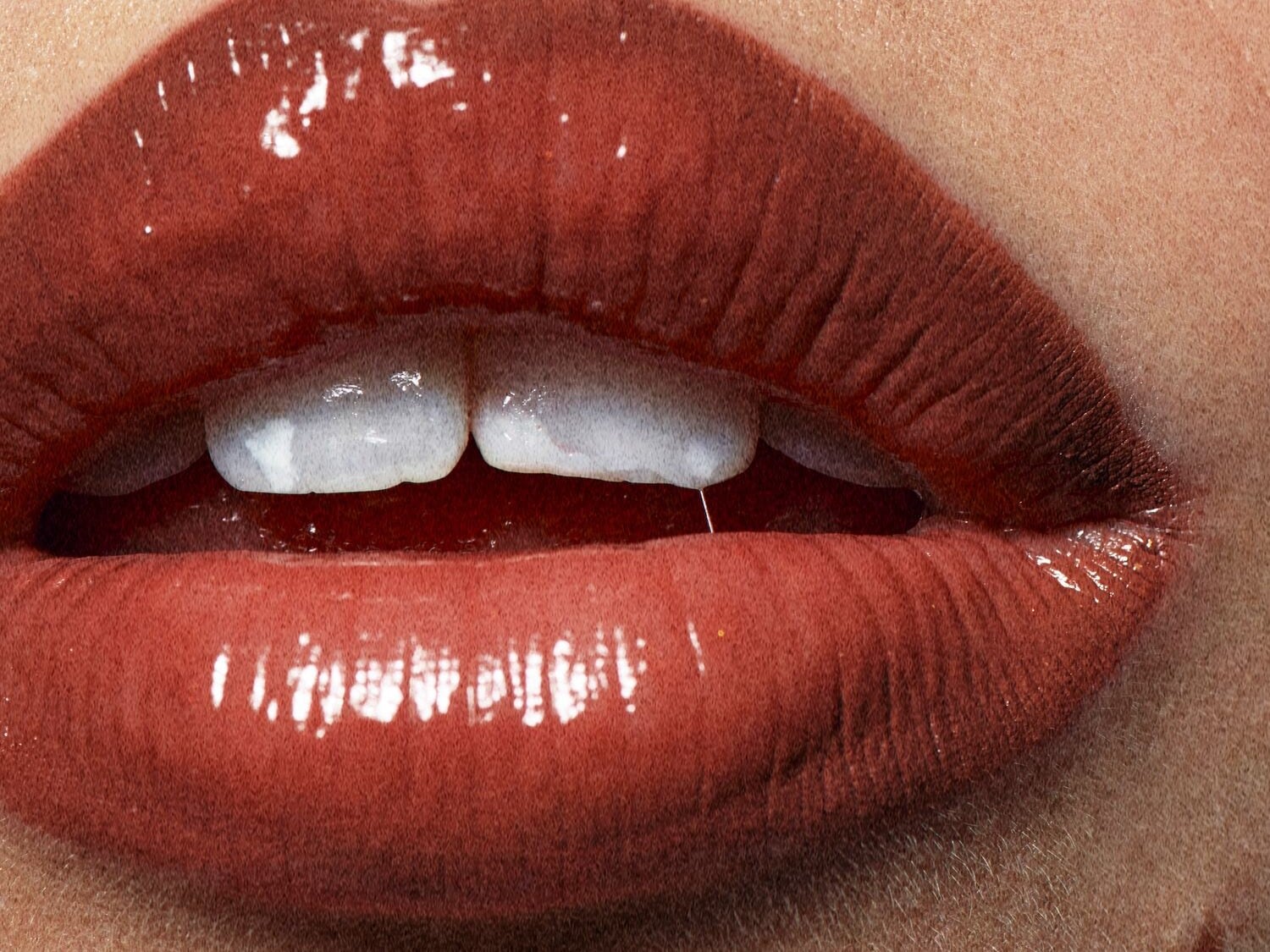 Nahaufnahme von glänzenden, korallenroten Lippen, die einen Hauch von Farbe und Glanz für einen vollen Schmollmund zeigen.