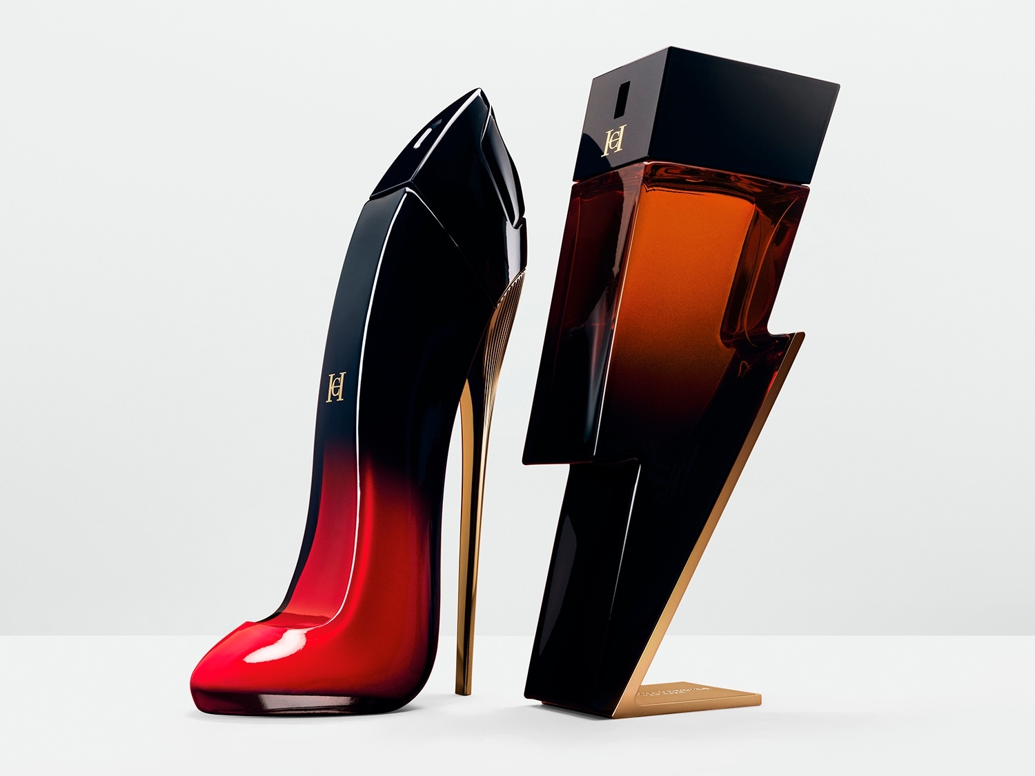 Zwei Parfümflakons, einer in Form eines schwarzen und roten High Heels mit goldenem Absatz, der andere in Form eines Blitzes mit bernsteinfarbenem Farbverlauf und schwarzem Deckel.