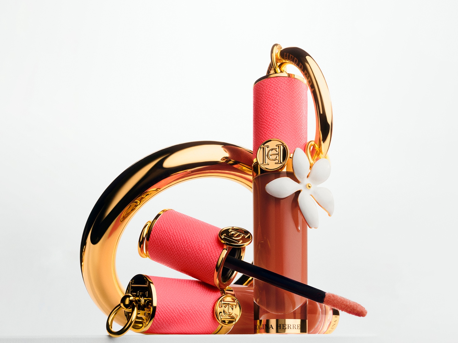 Entdecke den Carolina Herrera Lippenstift: ein luxuriöses Accessoire mit korallfarbenem Etui, goldenen Akzenten und einem zarten weißen Blütenanhänger.
