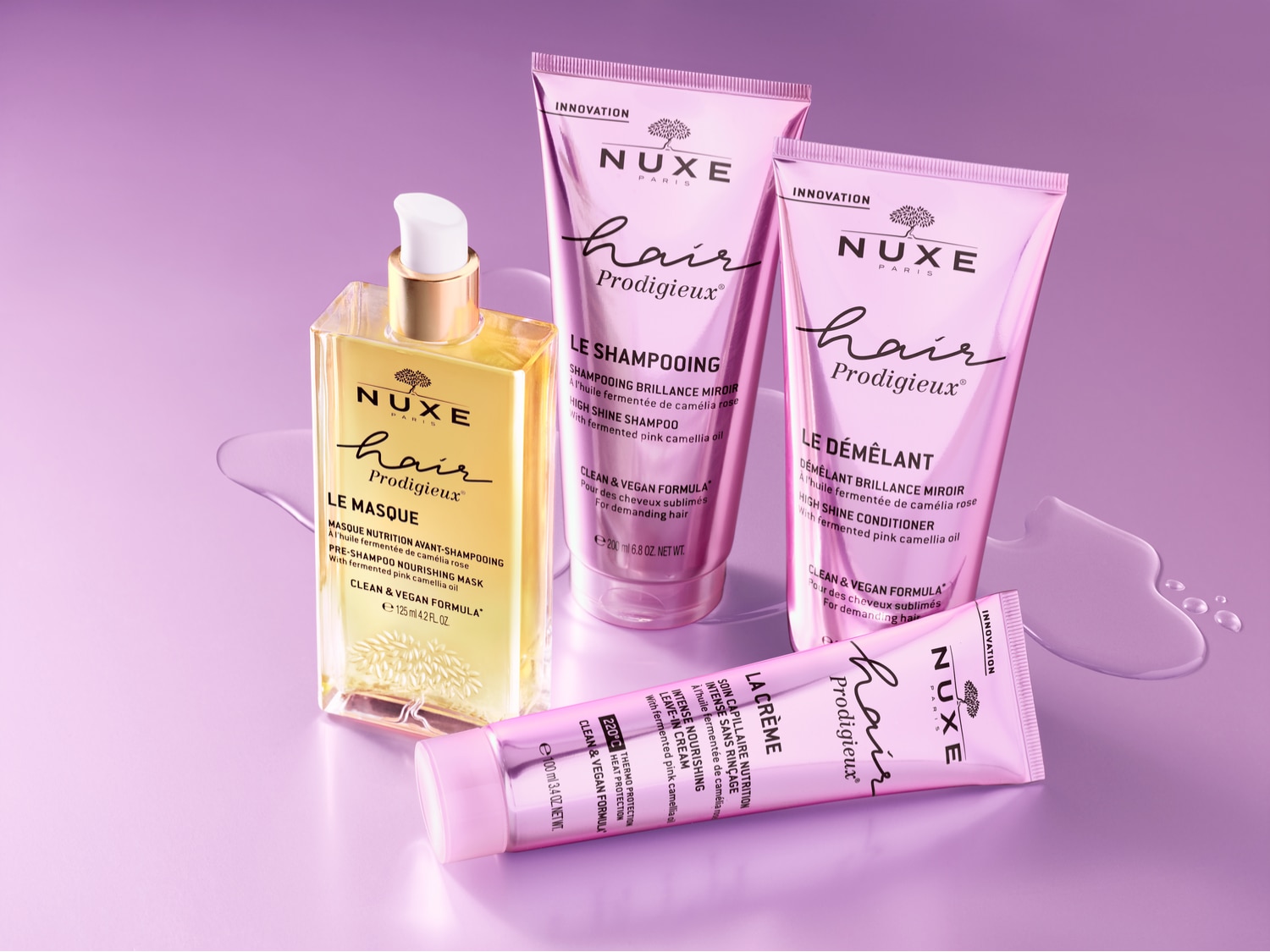 Nuxe Hair Prodigieux-lijn met gouden maskerfles en roze verpakkingen voor shampoo, conditioner en crème, voor een complete haarverzorgingsroutine.