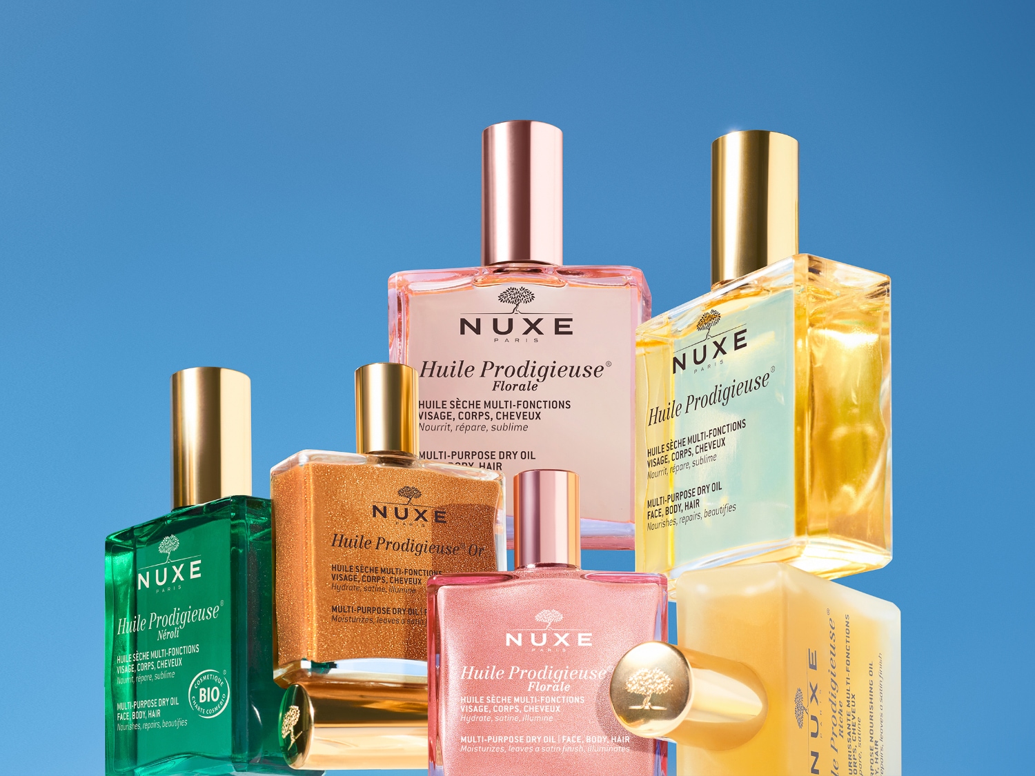 Een verzameling Nuxe Huile Prodigieuse multi-functionele droge oliën voor gezicht, lichaam en haar, in verschillende varianten en kleuren.