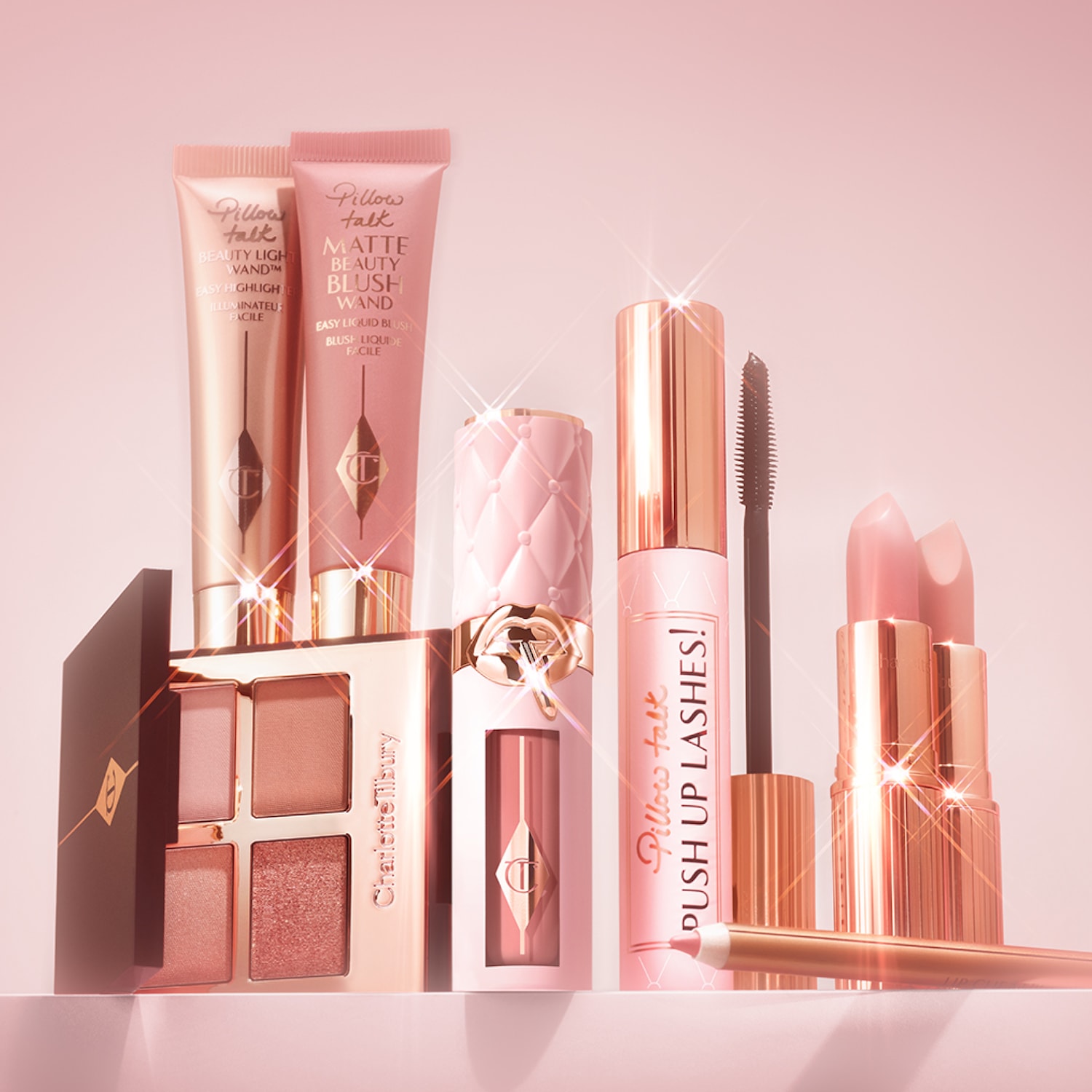 Eine Kollektion von Charlotte Tilbury Make-up-Produkten in Rosatönen, darunter Lidschattenpalette, Beauty Light Wand, Matte Beauty Blush Wand, Lippenstift, Lipliner und Pillow Talk Push Up Lashes Mascara.