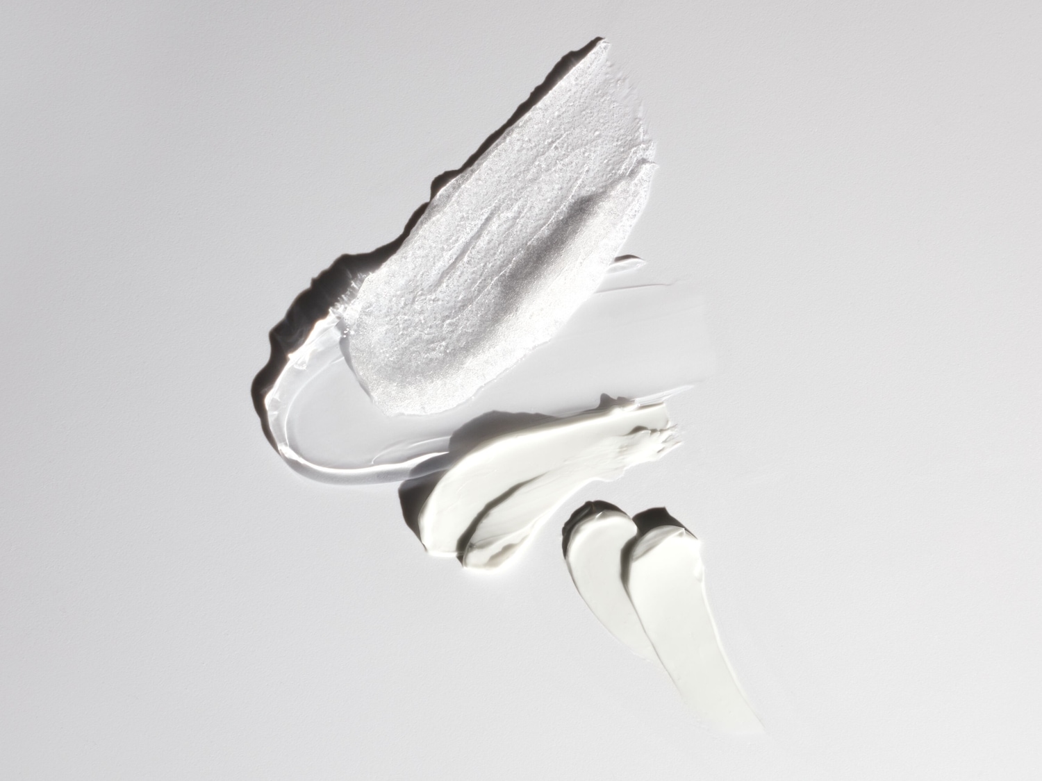 Ecco tre diversi tipi di consistenza di crema bianca, da una crema lucida e spessa a una crema più sottile e liscia.