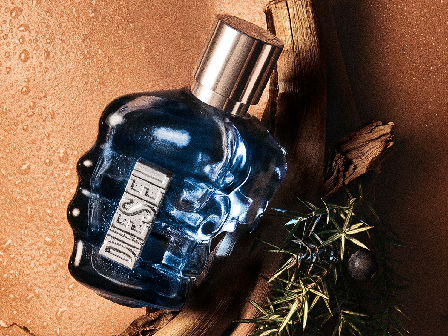 Une bouteille de parfum Diesel bleue en forme de poing repose sur du bois, avec des détails verts et des gouttelettes d'eau.