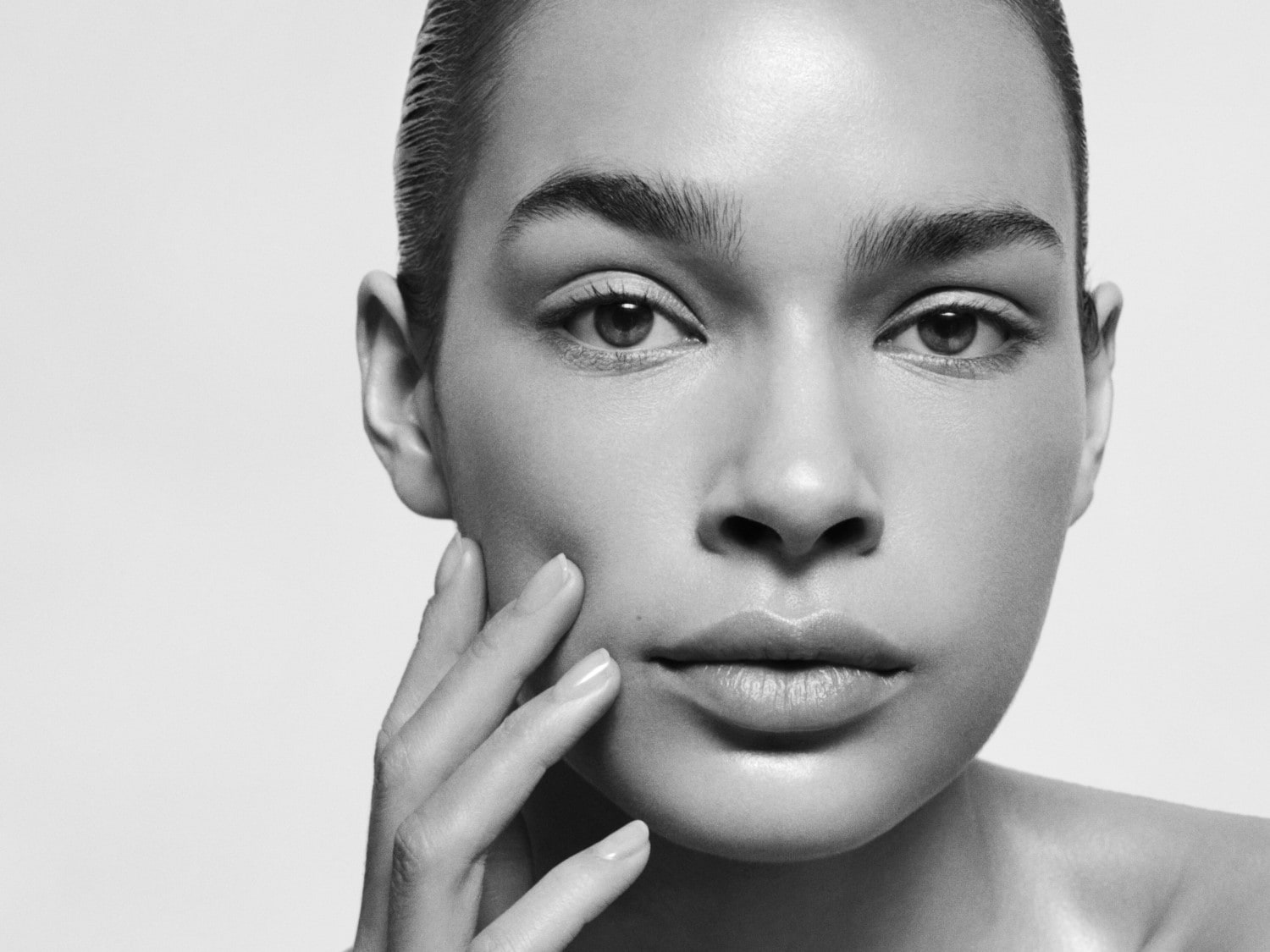 Nahaufnahme eines Frauengesichts in Schwarzweiß, ihre Hand berührt sanft ihre Wange.
