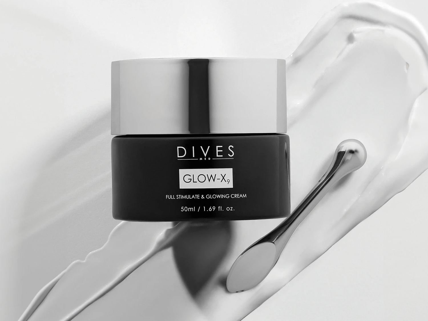 Czarny słoiczek kremu Dives Med Glow-X9 z srebrnym wieczkiem i aplikatorem na białym tle kremu. Krem stymuluje i rozświetla skórę, pojemność 50ml.